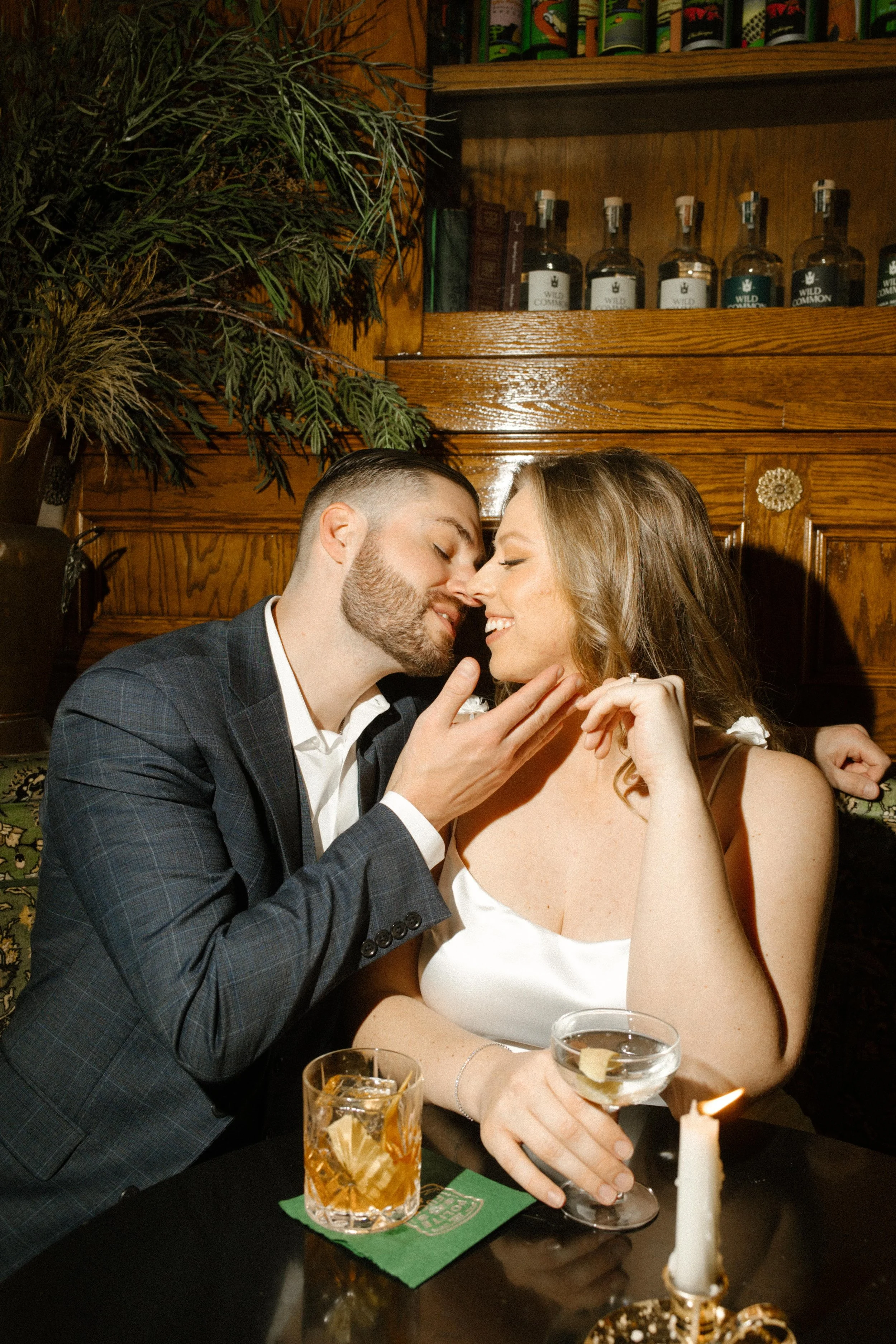 Couple leans in close, laughing and sipping cocktails at a moody bar in North Park — a dreamy stop during their San Diego engagement photos.