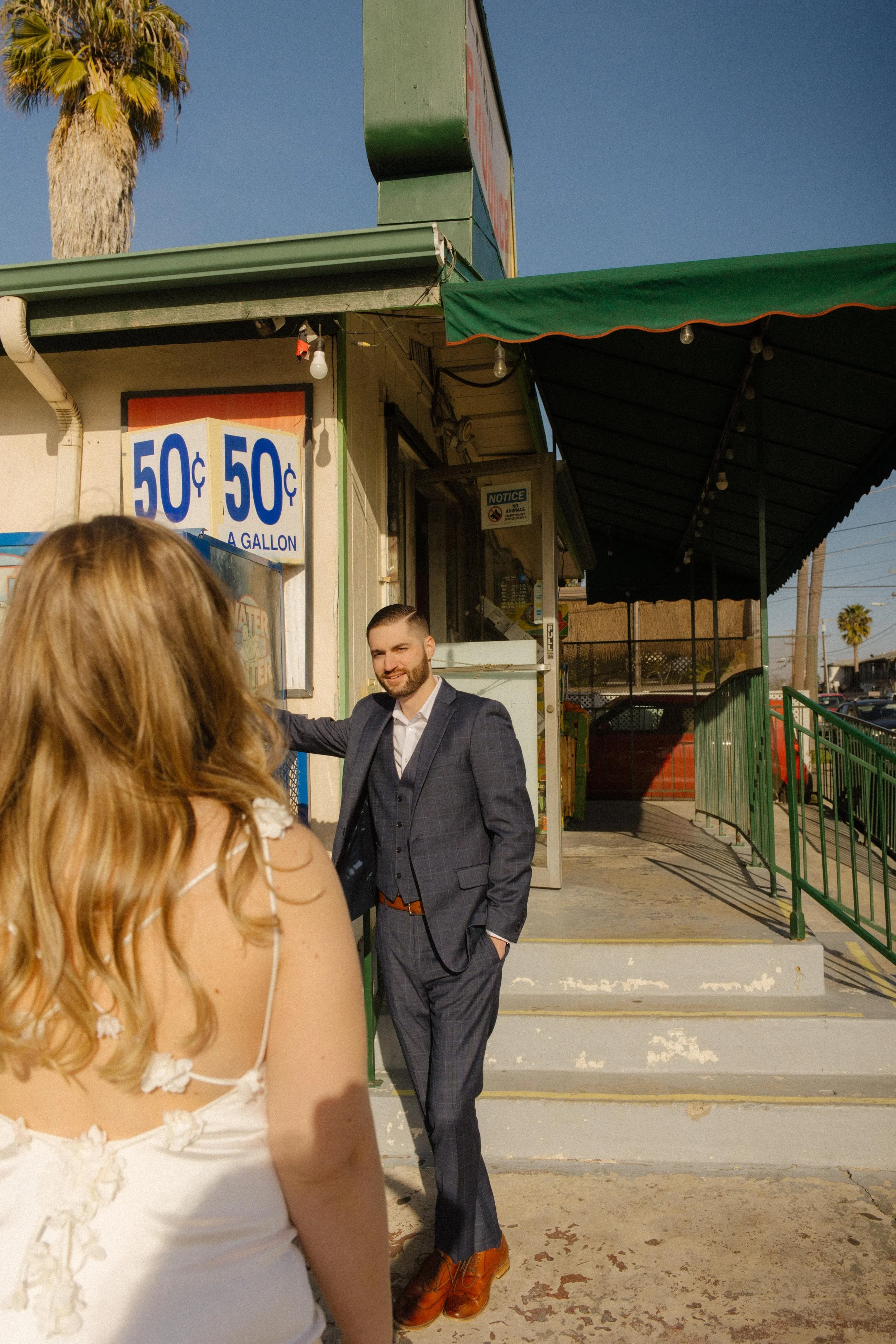 She approaches him with a smile in the sun-drenched street, the kind of moment that makes San Diego engagement photos feel personal and real.