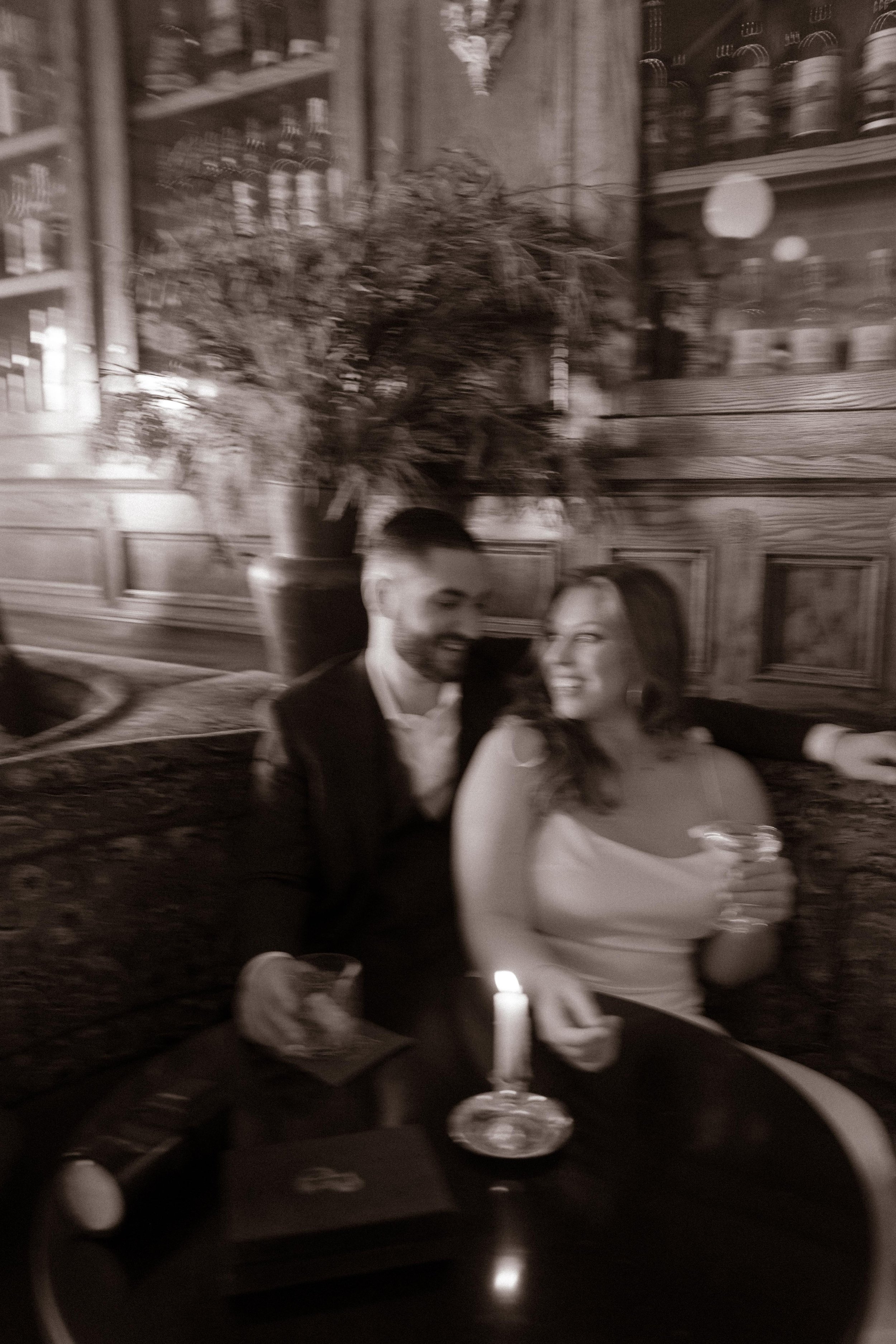 A blurry, joy-filled moment caught mid-laugh during a candlelit toast in this cozy San Diego engagement session.