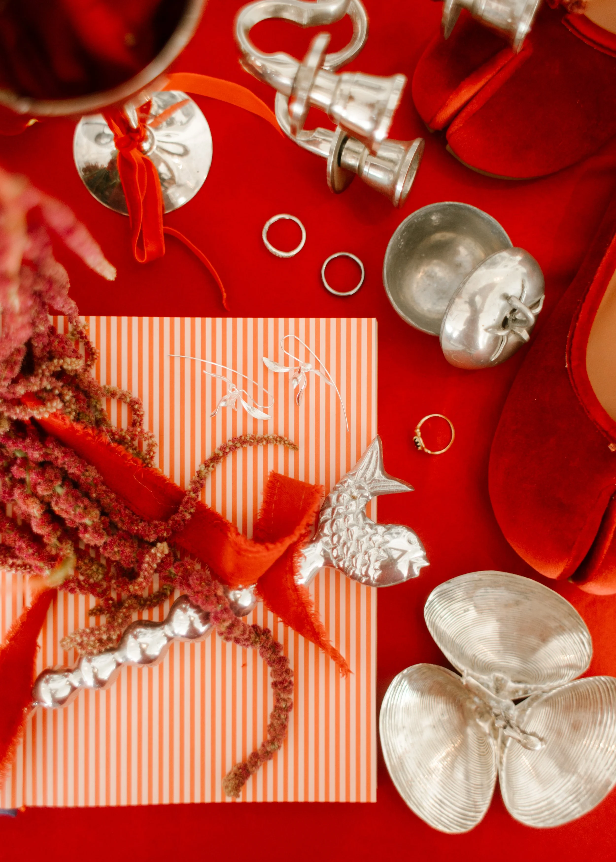 Flat lay of wedding rings, red accessories, and silver details on a vibrant red background