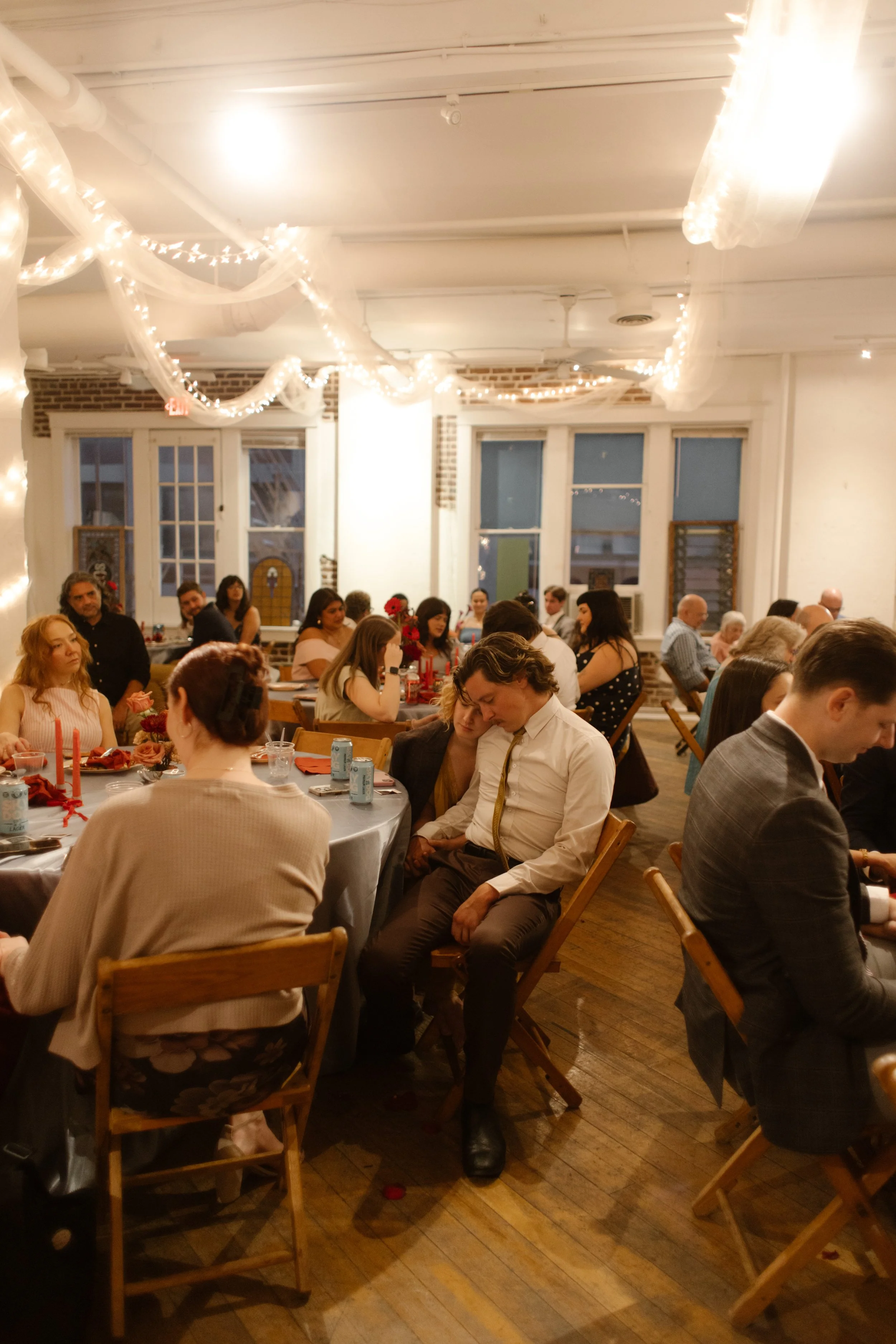 Guests gathered for dinner under soft string lights, sharing conversation and cozy connection
