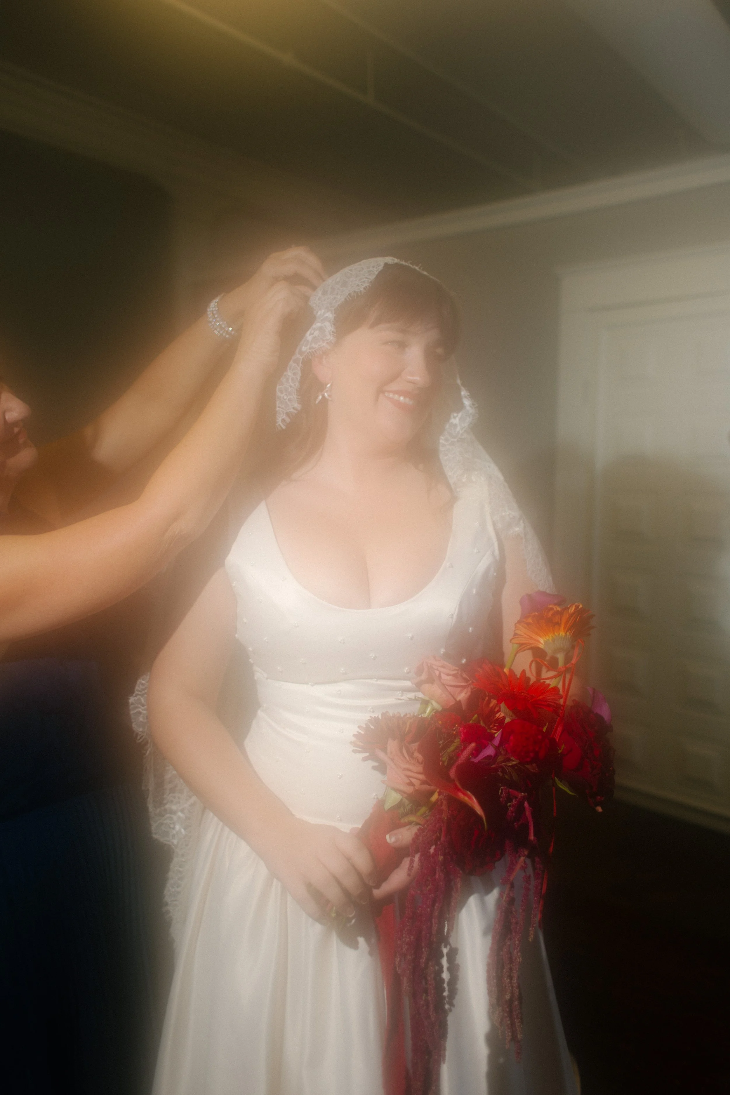 Dreamy, glowy portrait of the bride getting her lace veil adjusted before the ceremony