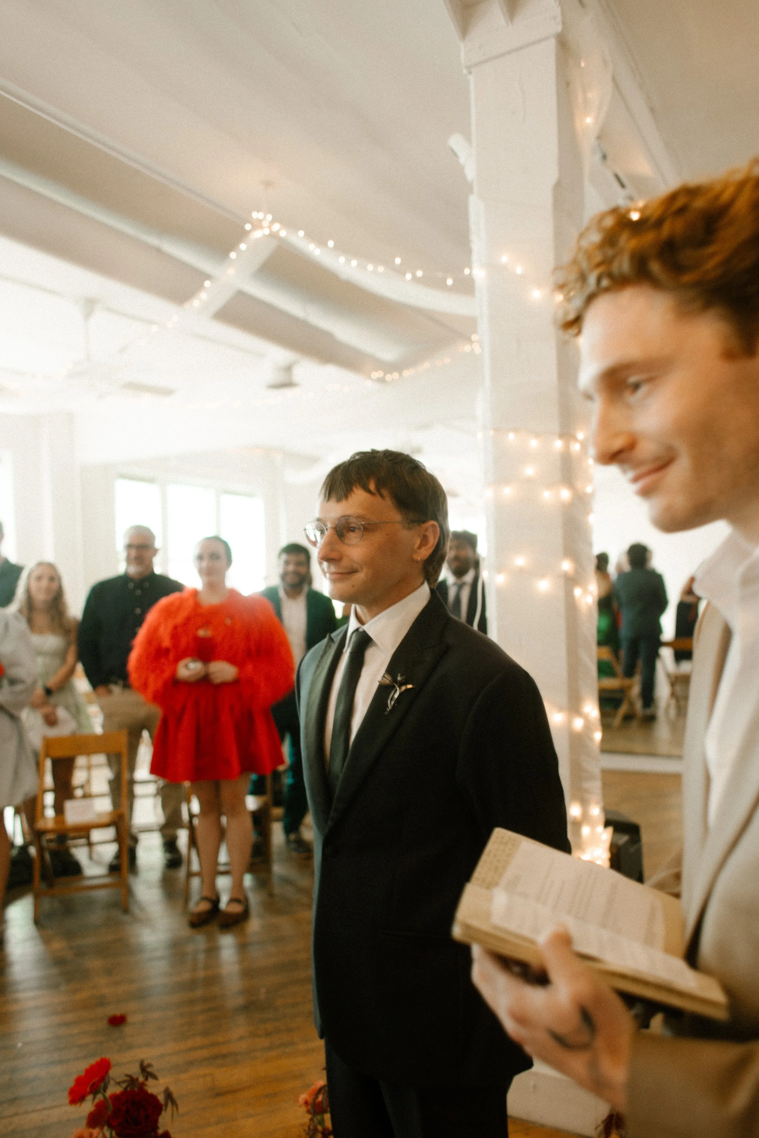 Groom smiling at the altar, surrounded by guests and glowing string lights at a Tennessee wedding