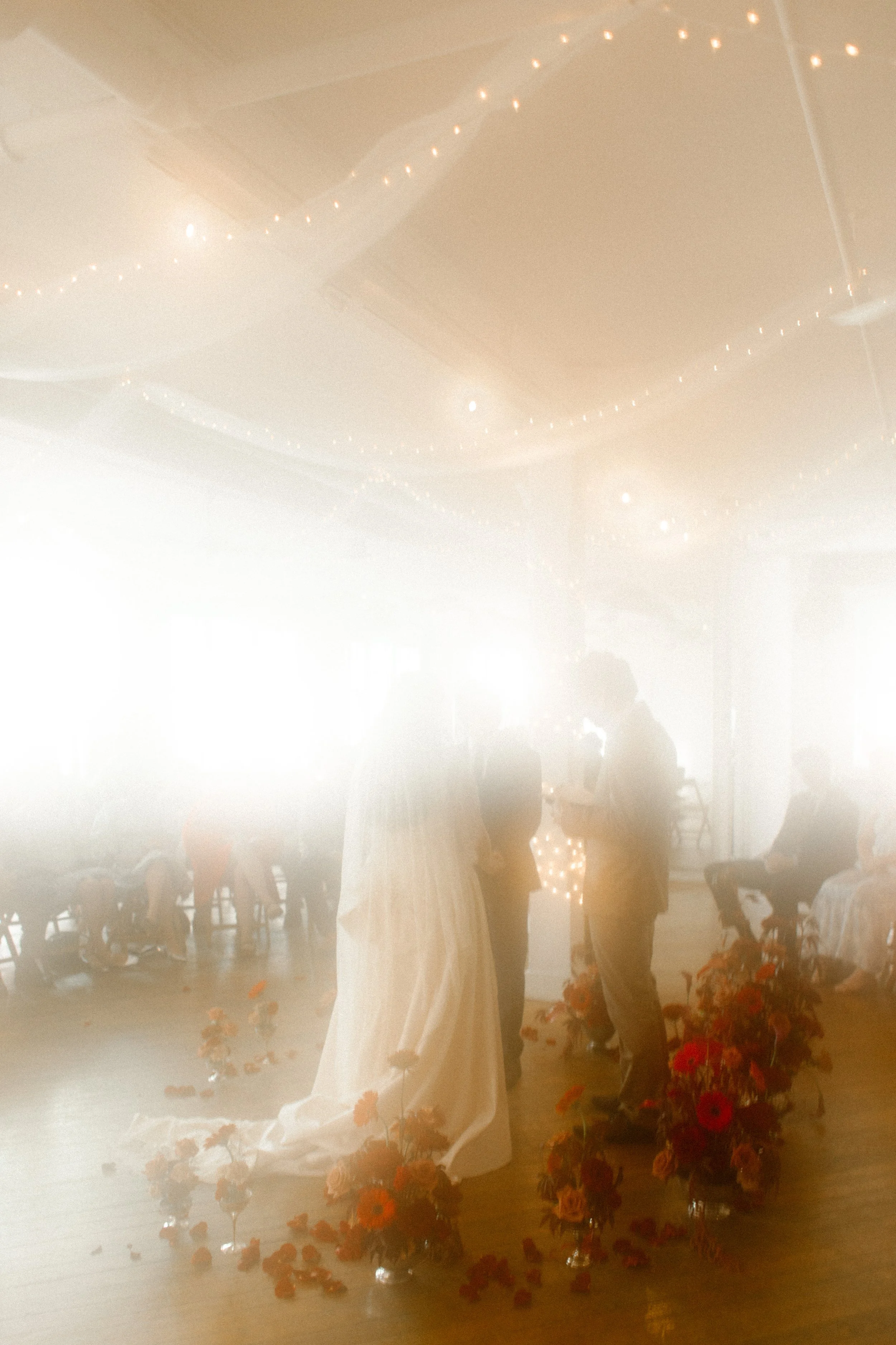 Dreamlike view of the couple exchanging vows surrounded by red florals at their Tennessee wedding