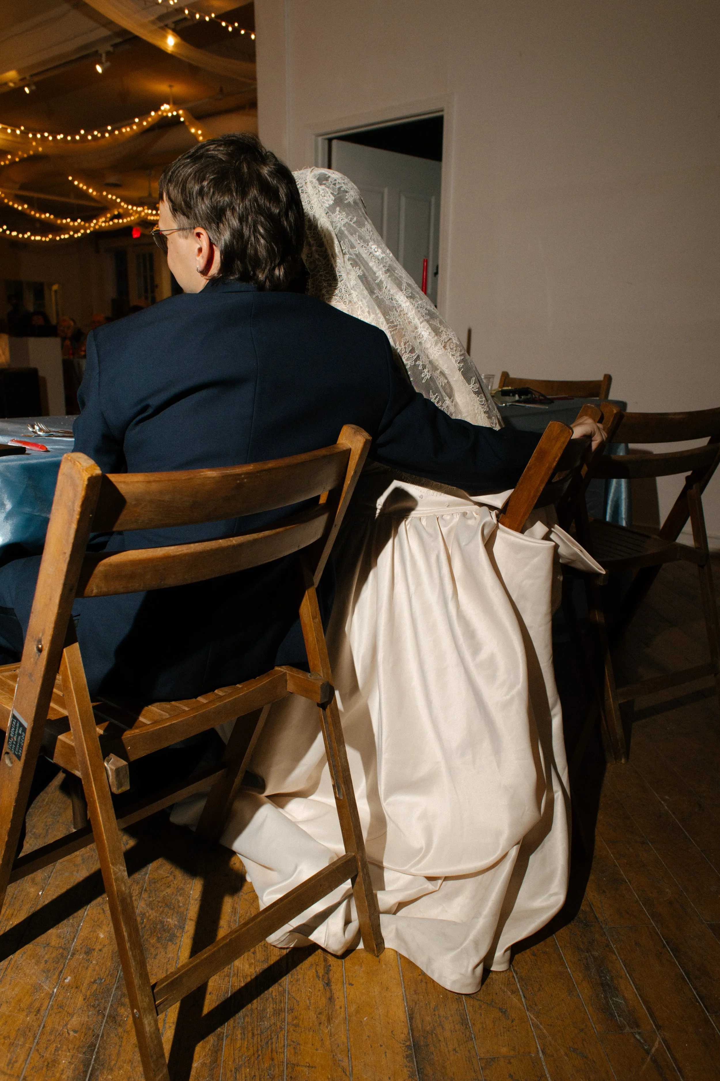 Quiet moment between the couple at the dinner table, her gown draped over the chair