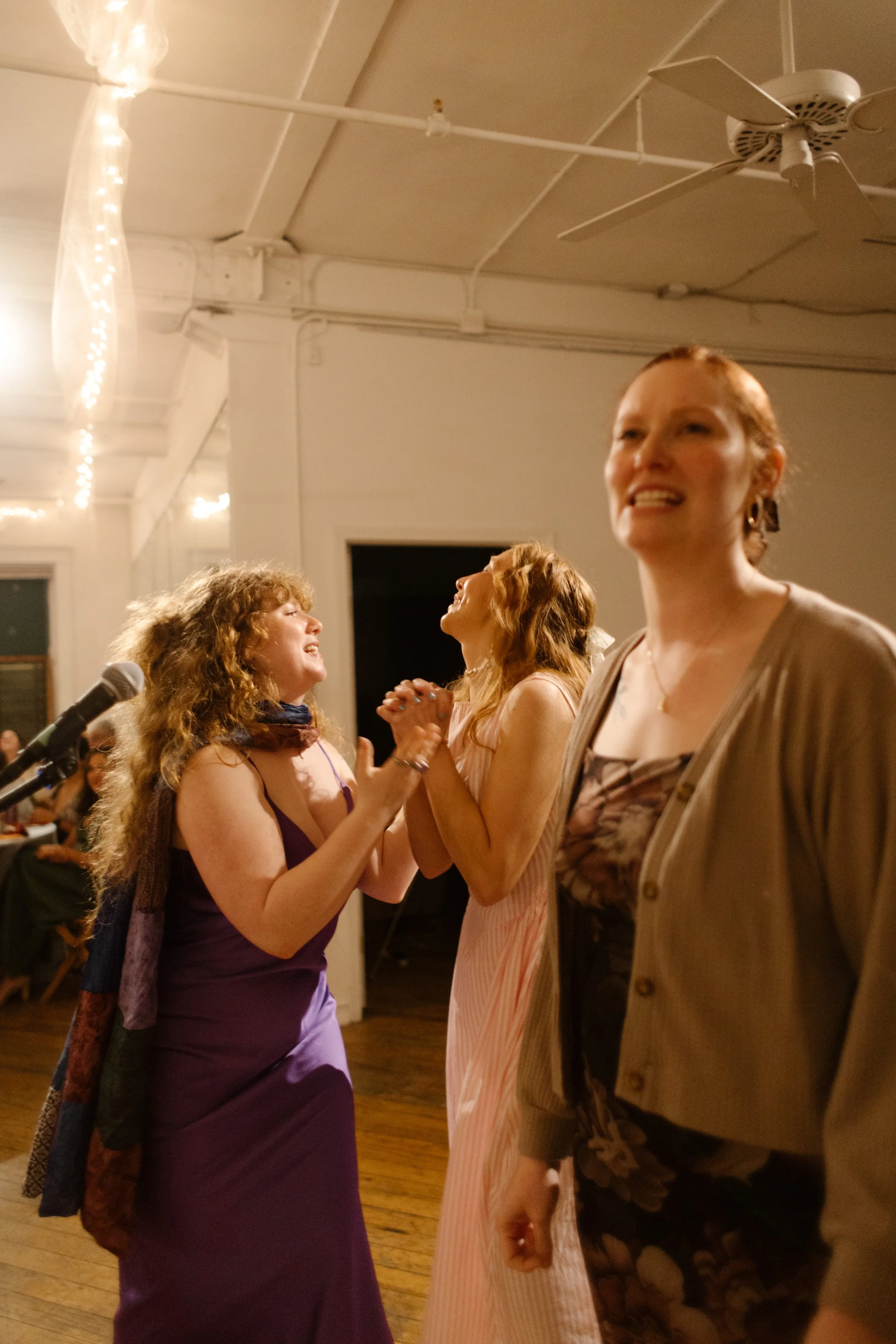 Reception guests laugh and sing into the mic during karaoke night celebrations