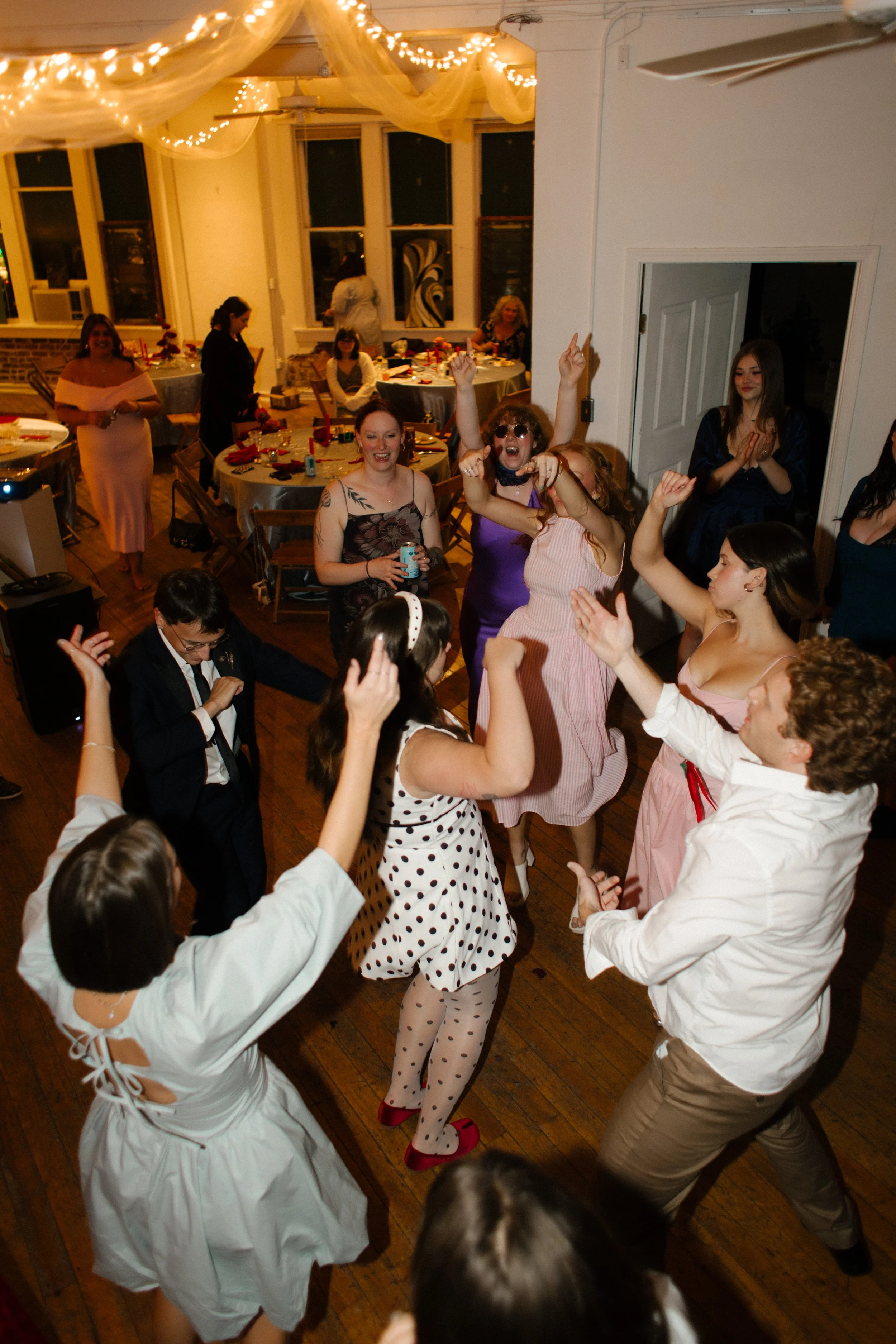 Guests raise hands in the air celebrating recent marriage and dancing together