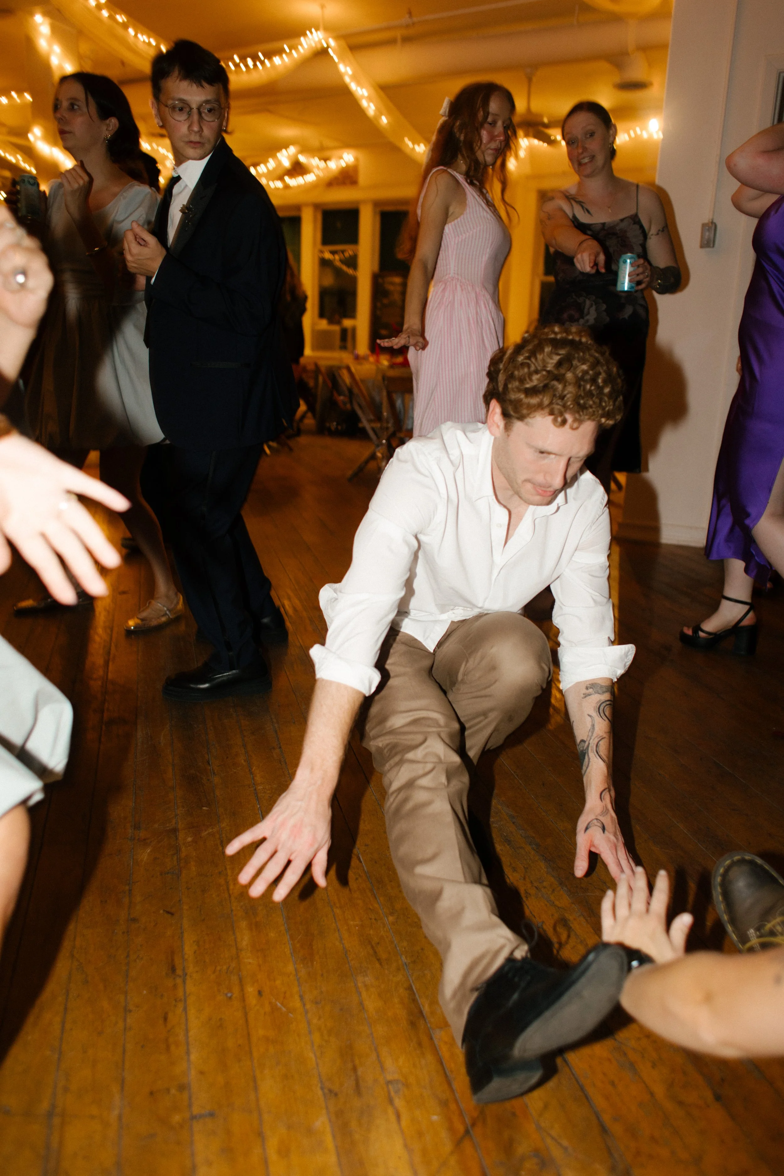 Reception guest wearing white shirt and khakis breakdancing on the dance floor after Tennessee wedding