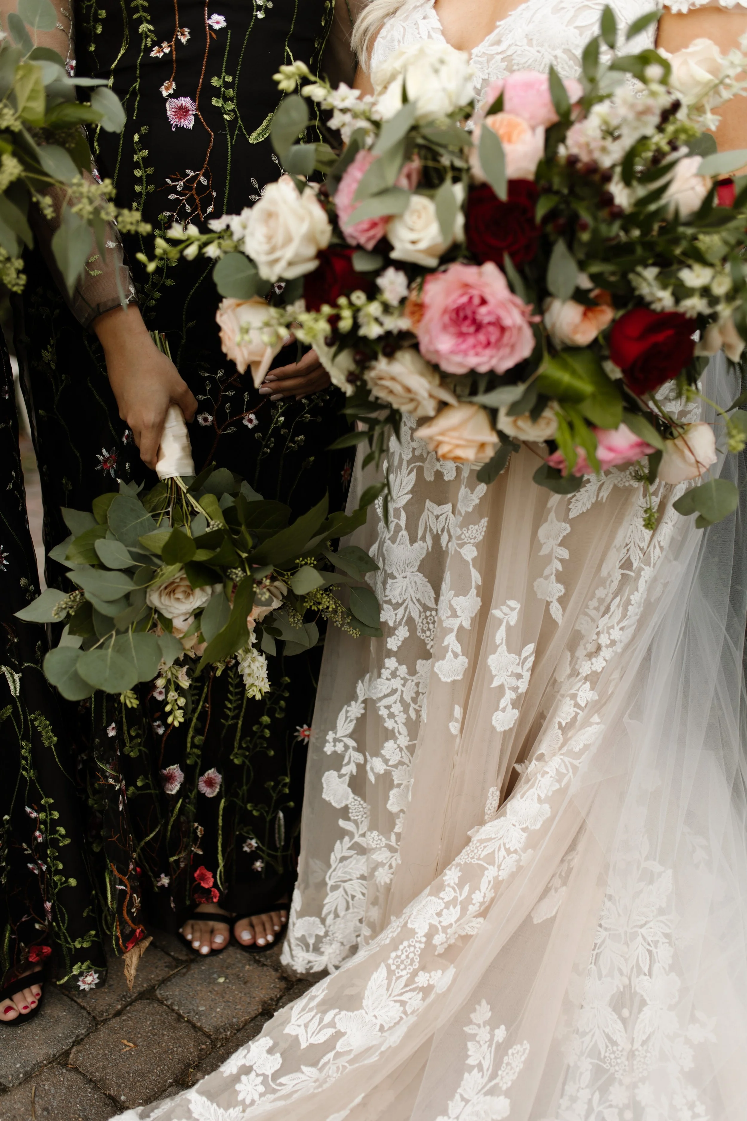 Romantic bouquet of red, blush, and cream roses against a lace wedding gown at an italy inspired wedding with earthy, garden-inspired florals.