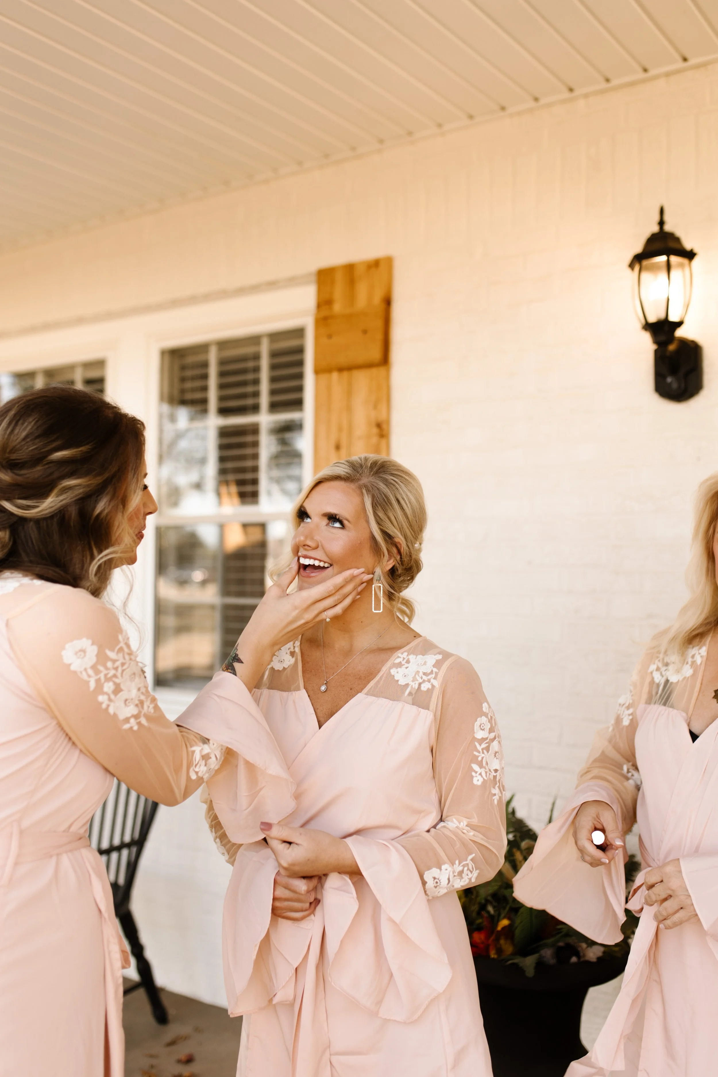 Bridesmaids in blush robes laughing together outside a Mediterranean-style venue during an italy inspired wedding morning.