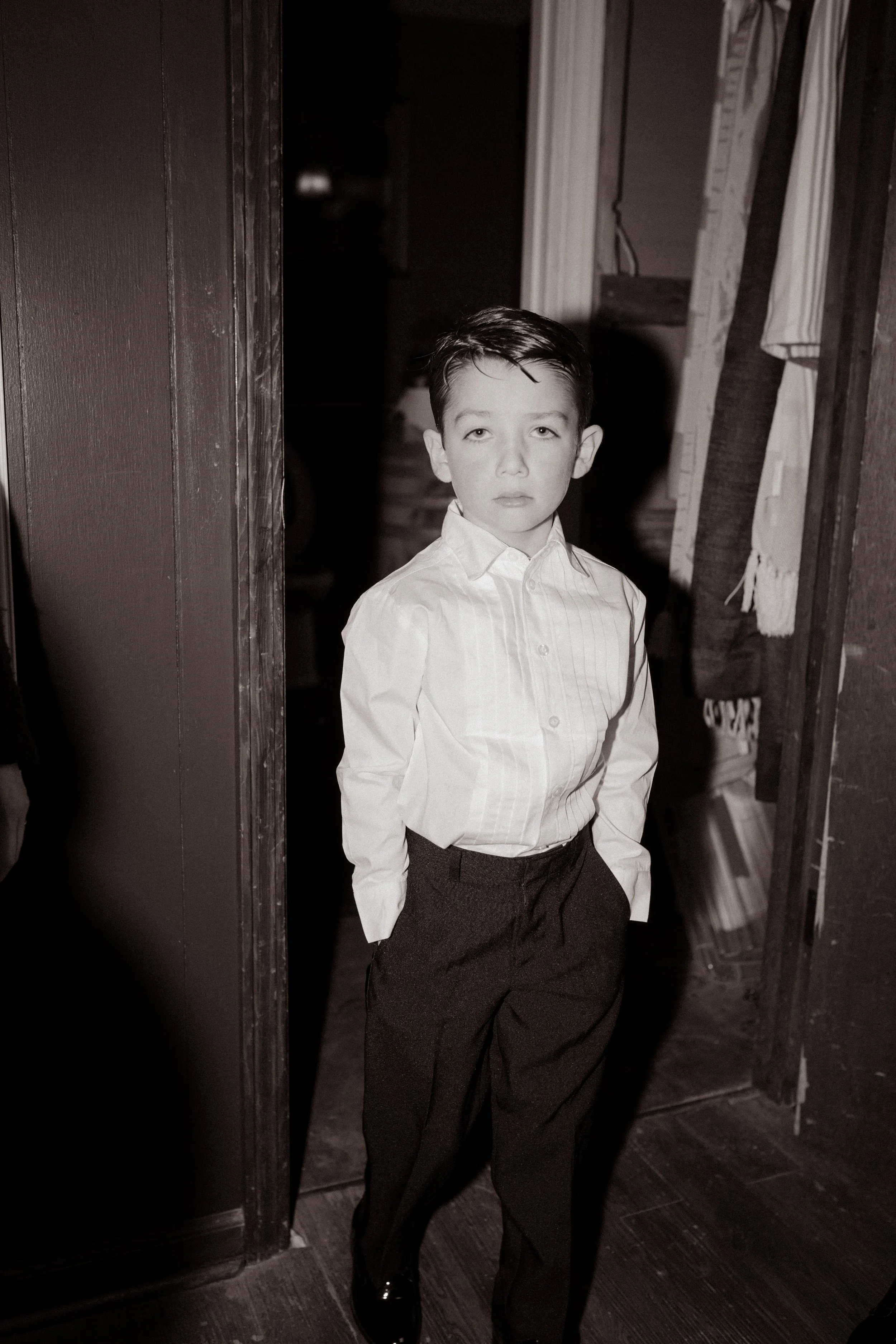 Black and white portrait of a young ring bearer standing in a doorway