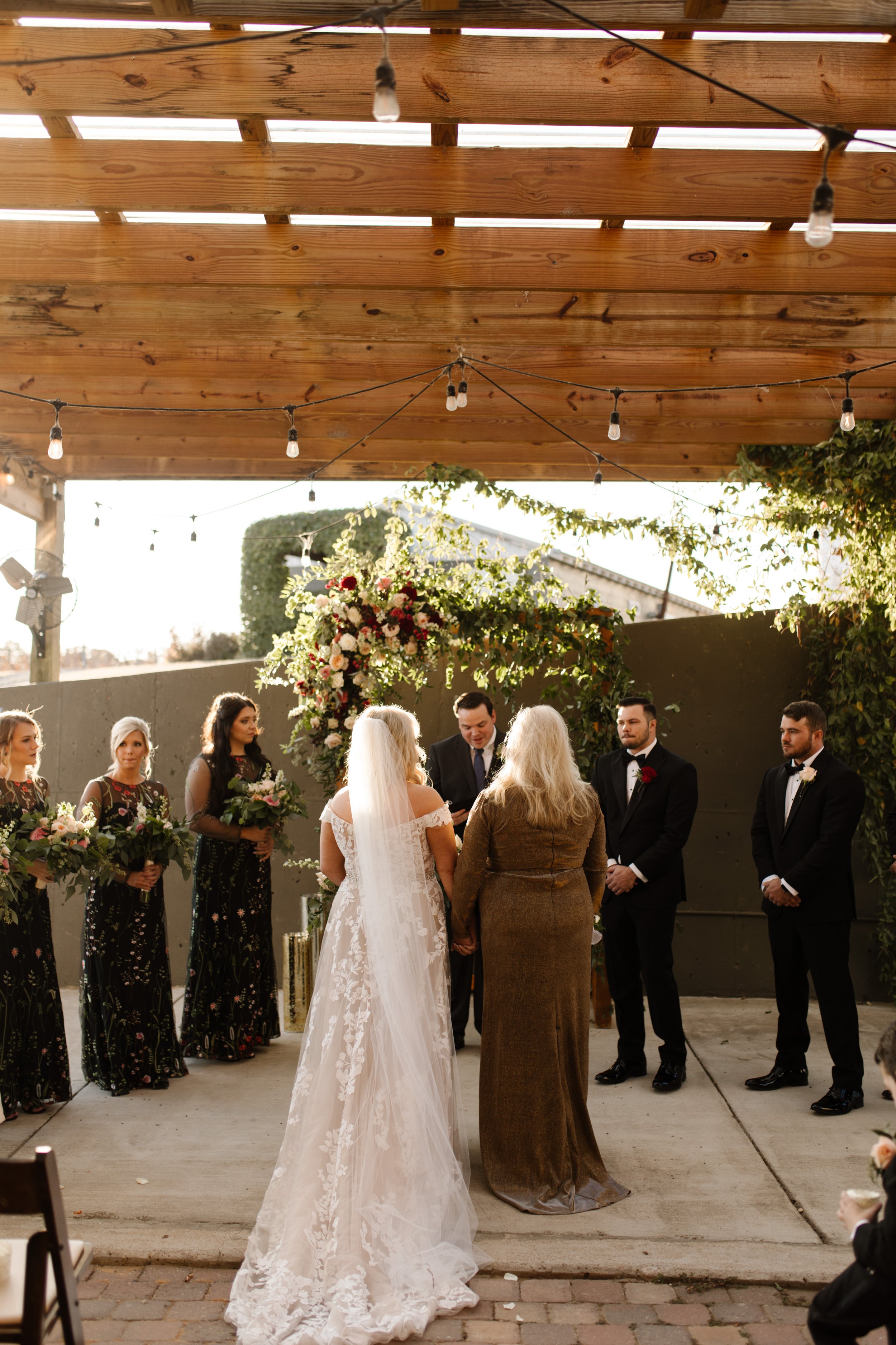 Bride and groom standing at the altar with wedding party beside them during an outdoor italy inspired wedding ceremony.