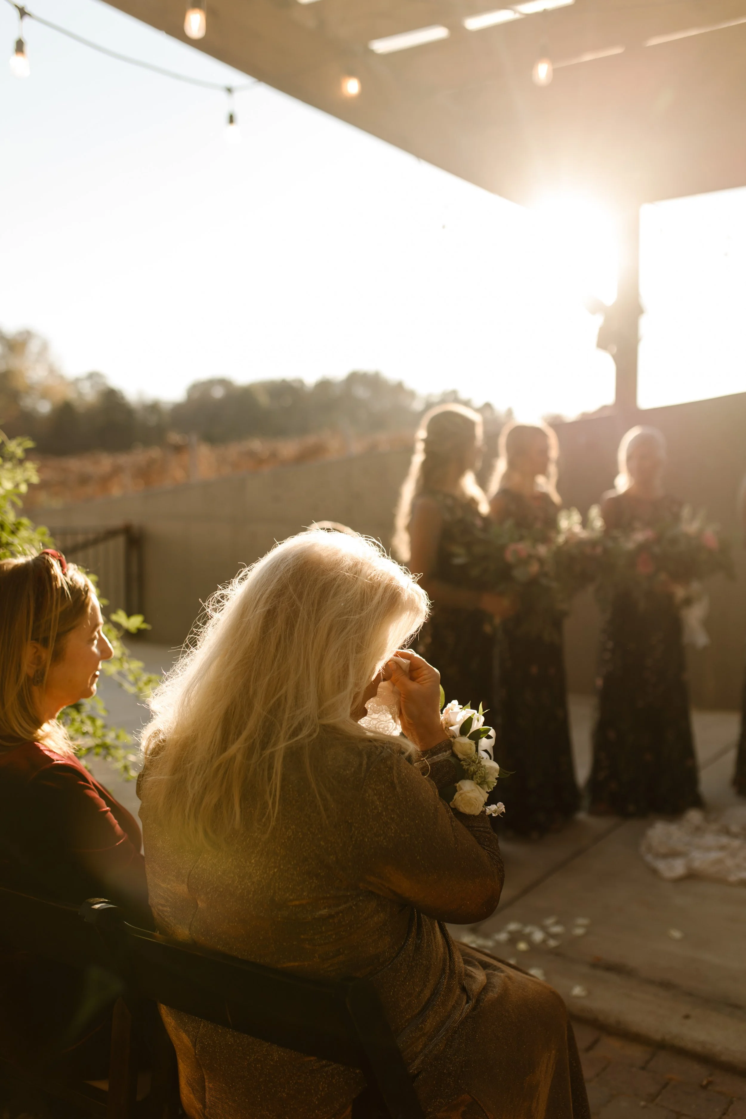 Emotional wedding guest wiping away tears during the ceremony at an italy inspired wedding in soft sunset light.
