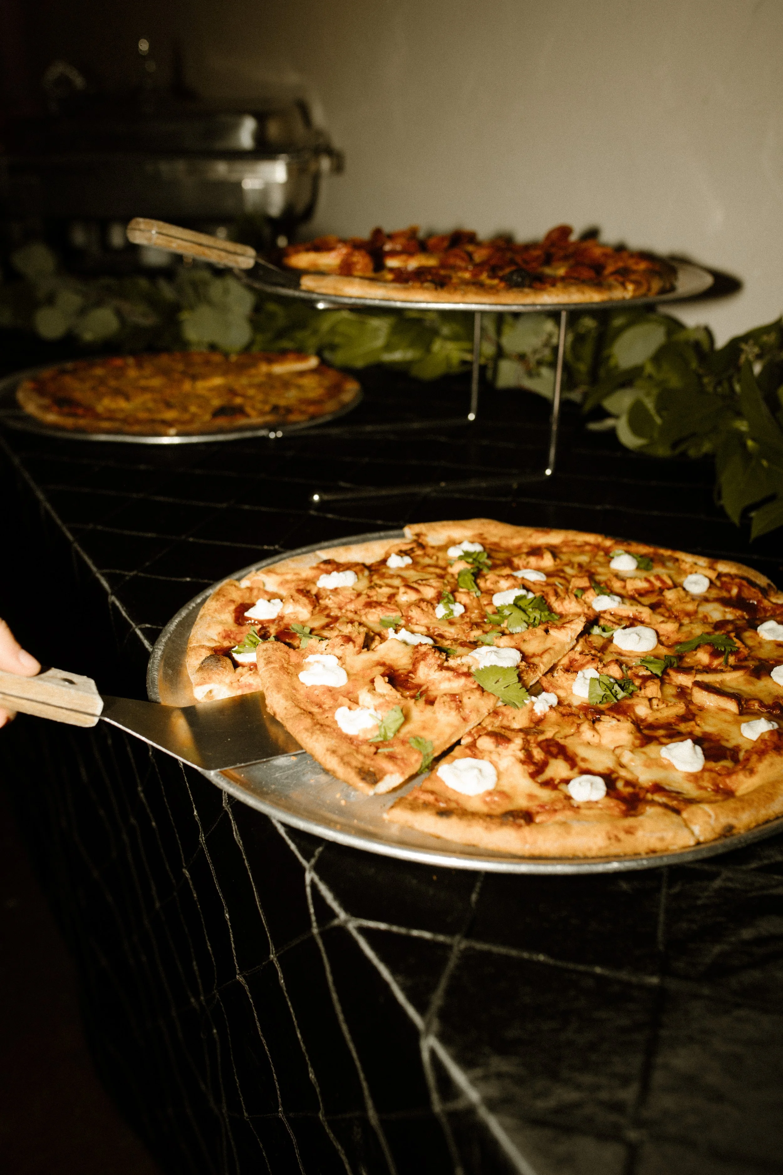Freshly served pizzas on display at a late-night italy inspired wedding reception with rustic, candlelit ambiance.