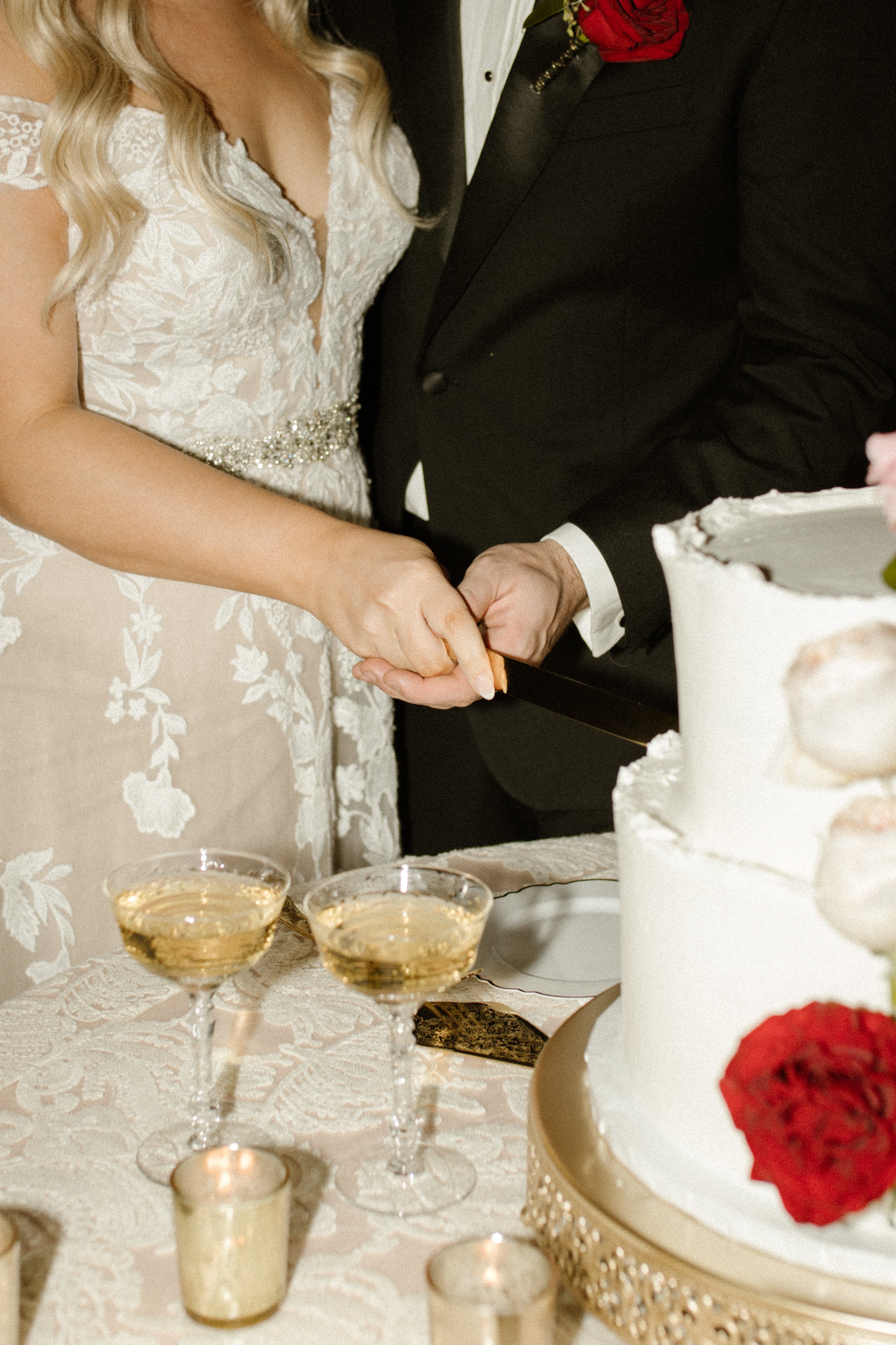 Bride and groom cutting their wedding cake together at an elegant italy inspired wedding reception with champagne coupes and candlelight.