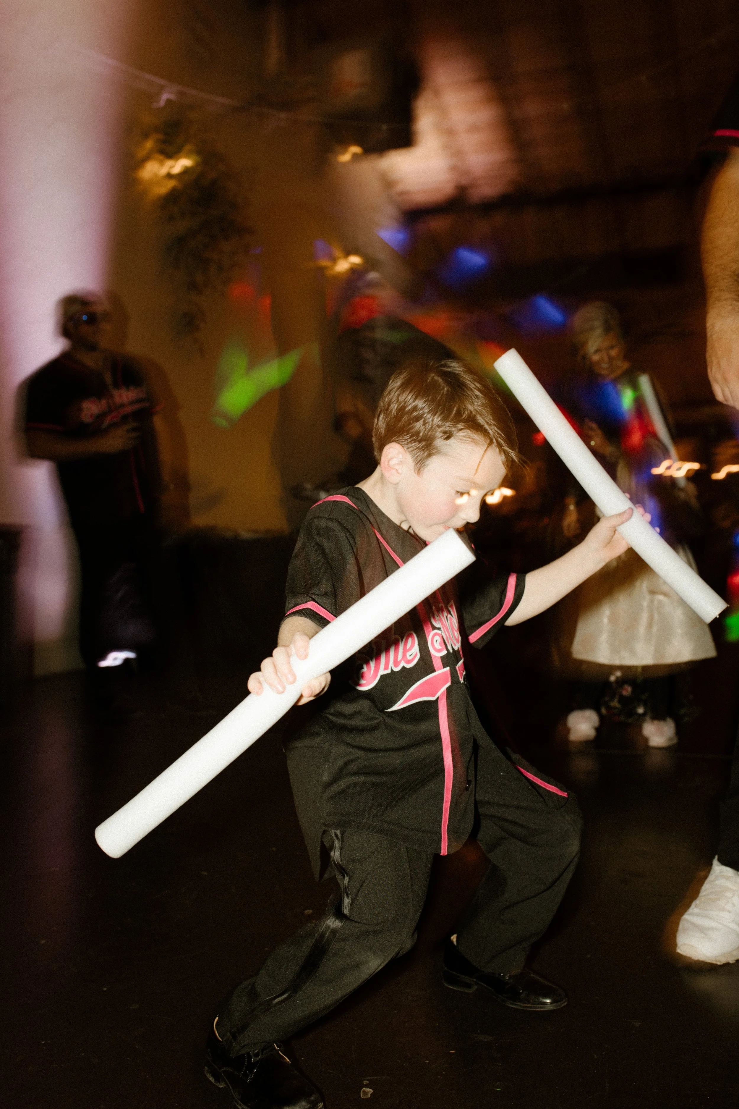 Young wedding guest dancing with glow sticks on the dance floor during a lively italy inspired wedding reception.