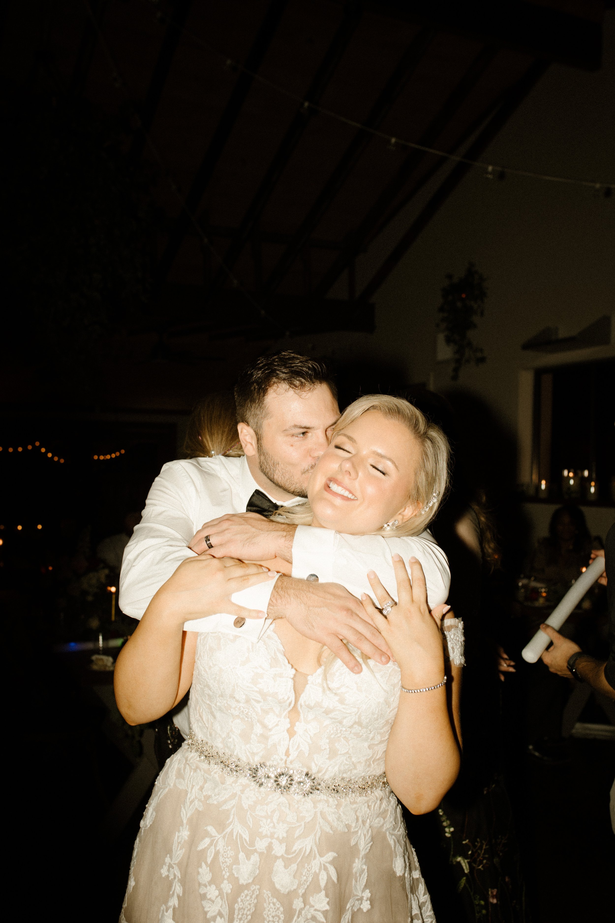 Groom wrapping his arms around the bride during a joyful dance floor moment at their italy inspired wedding.