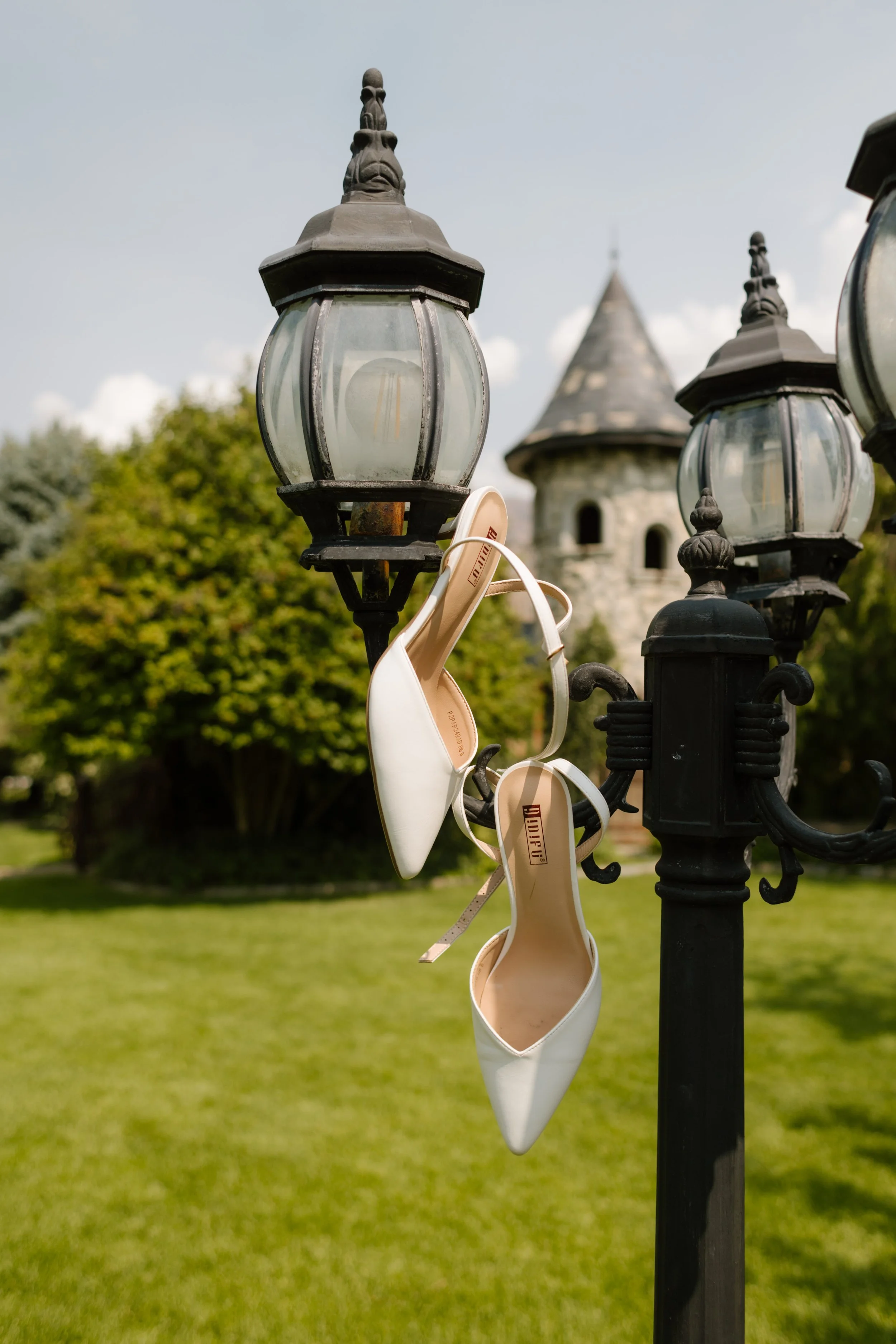 Bride's shoes hanging from antique lamp post at castle-inspired utah wedding venue