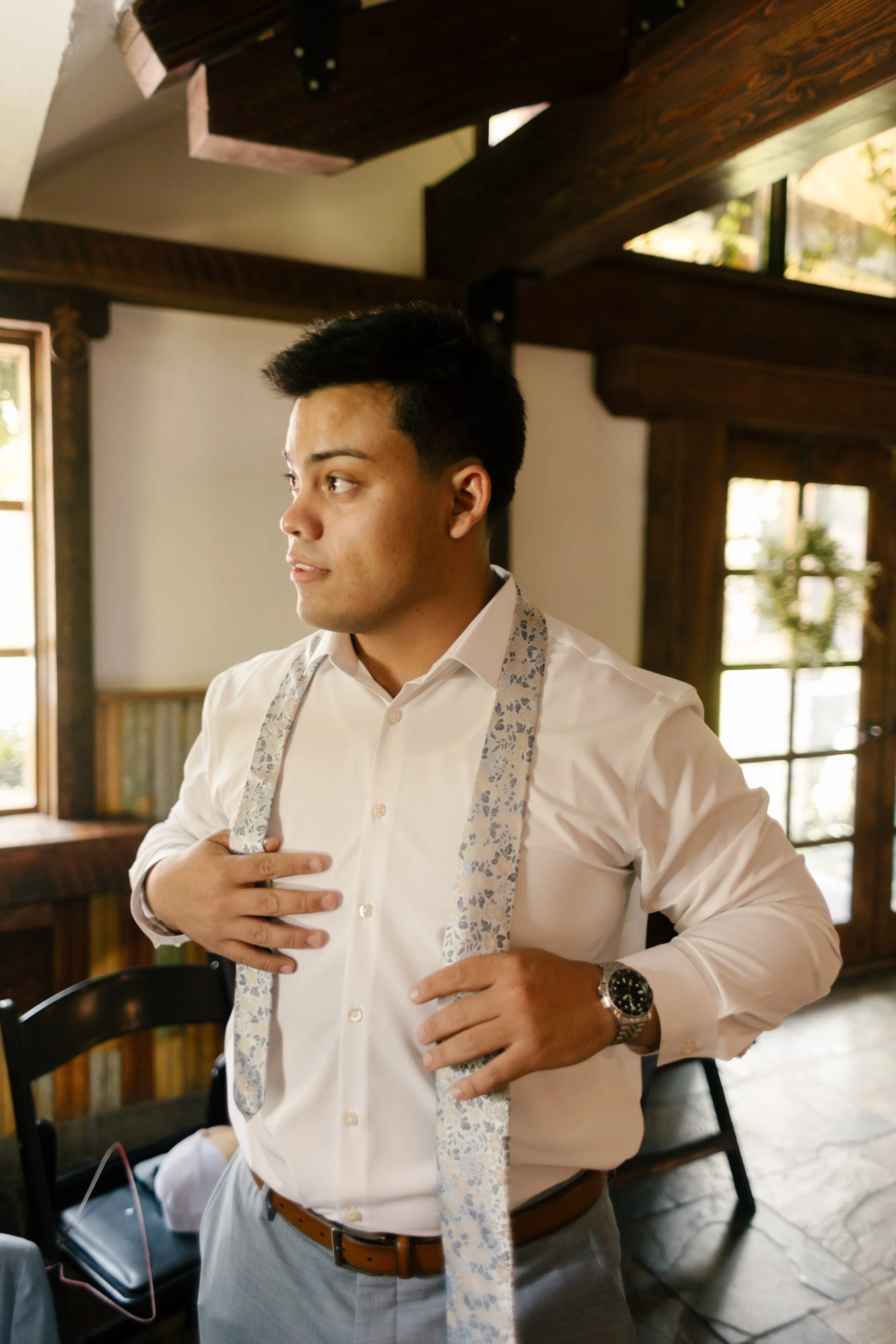 Groom with tie around his neck as he gets ready 