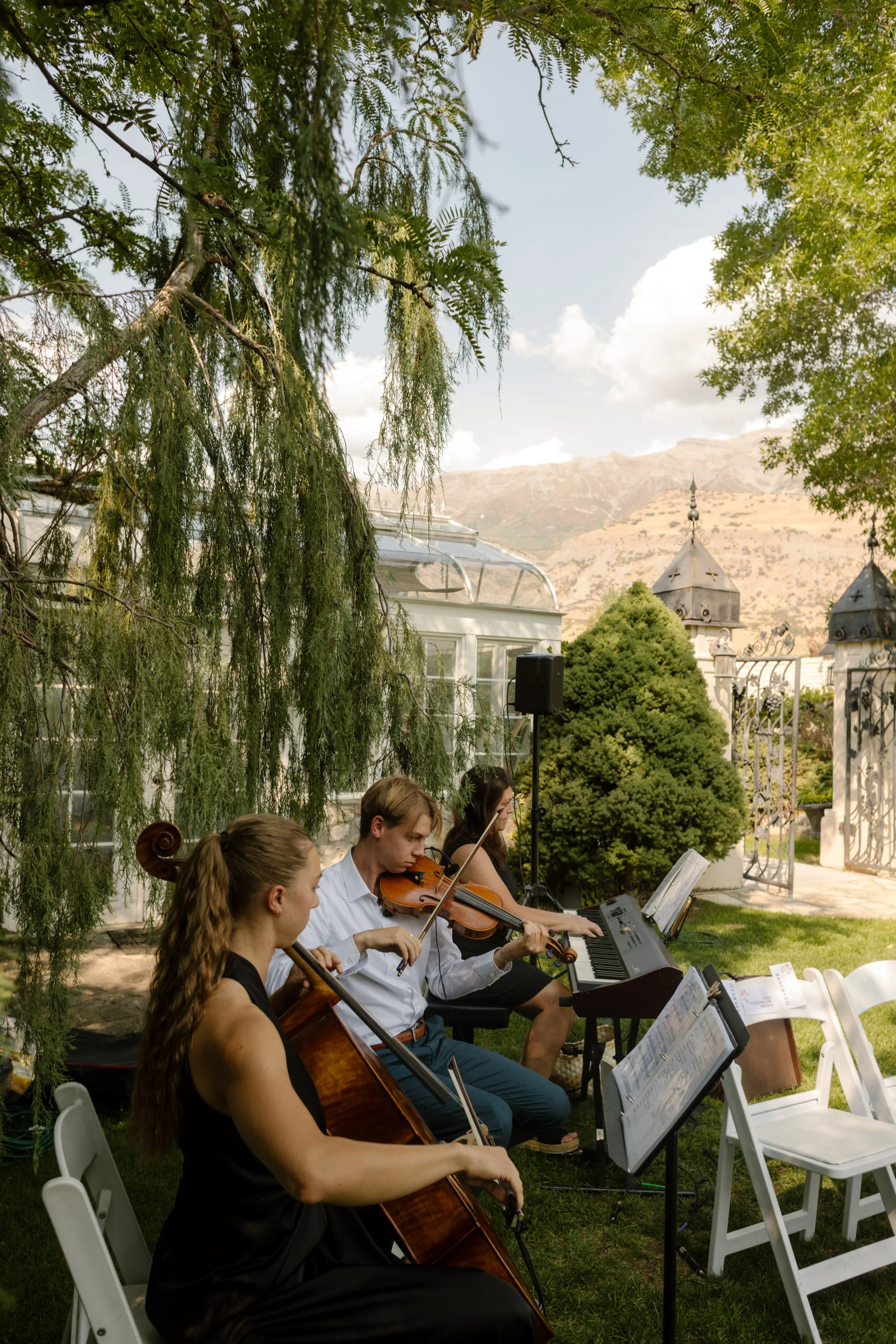 String musicians sitting together to play music at utah wedding venue outdoors.
