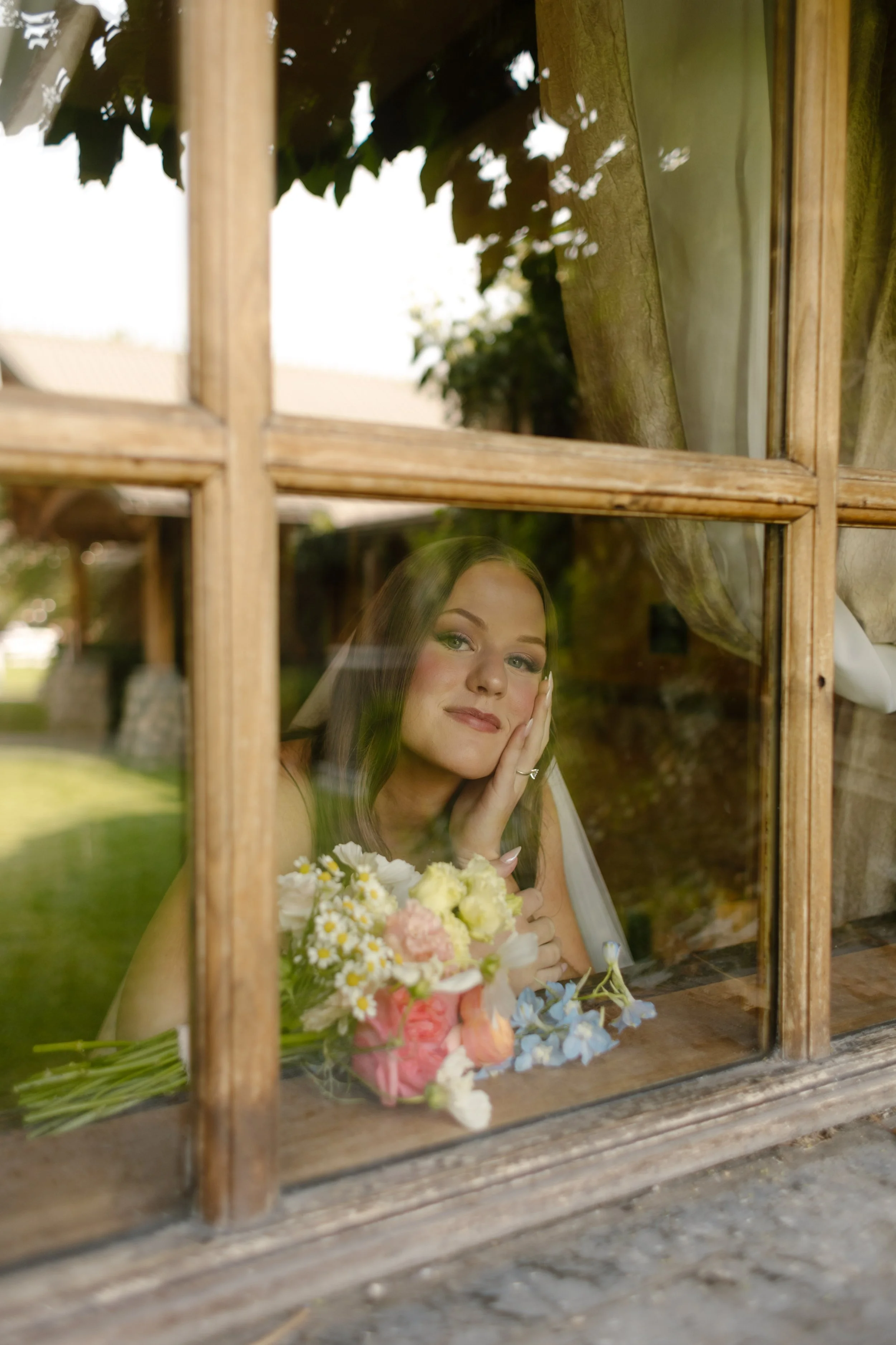 Bride looking dreamily outside your window with bouquet sitting in front of her before walking out to their wedding ceremony. 