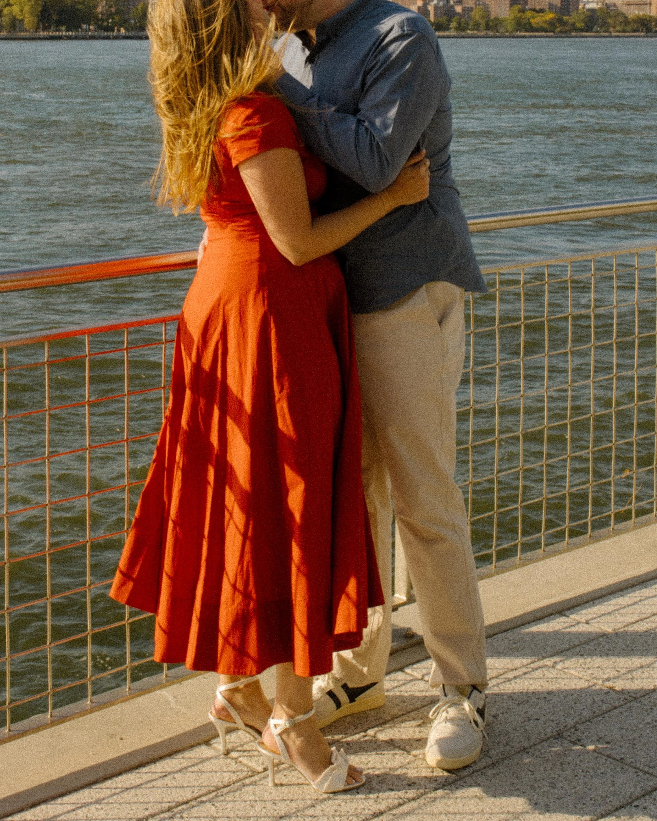 Intimate waterfront embrace during nyc engagement photos with skyline views across the river.