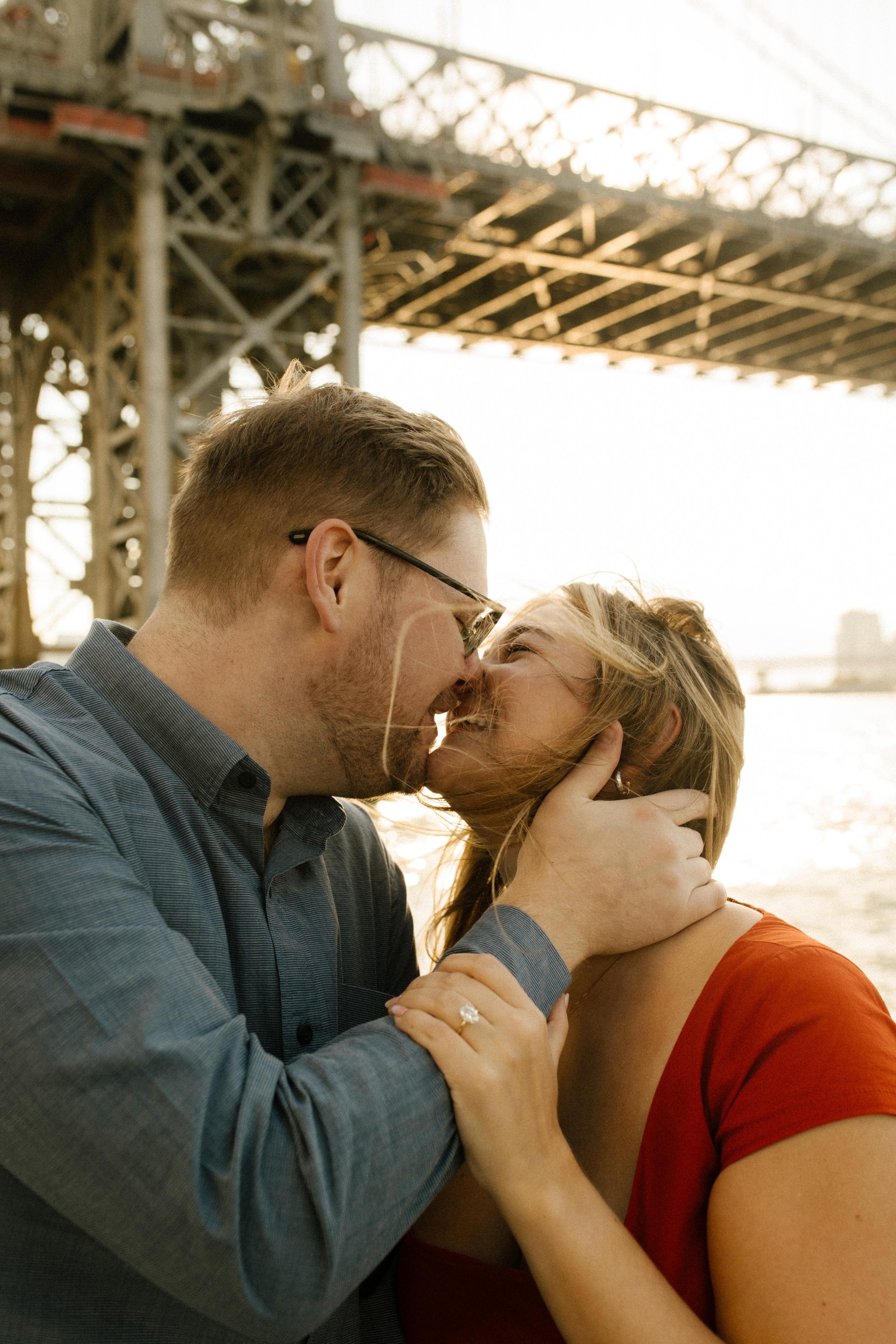 Intimate nyc engagement photos of couple kissing with golden sunset light reflecting off the water.