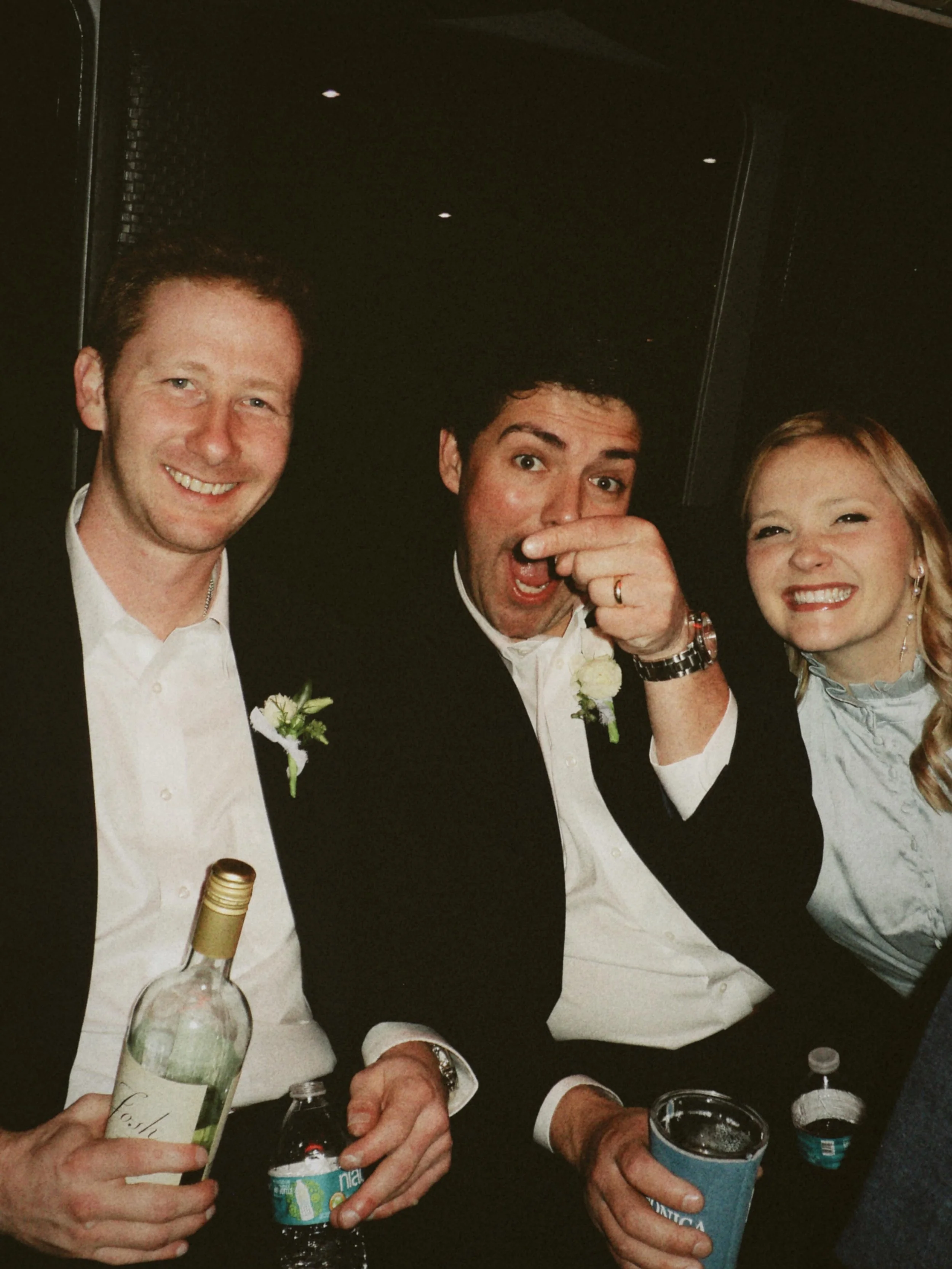 Wedding guests smiling and joking together while holding drinks during a lively late night wedding celebration.