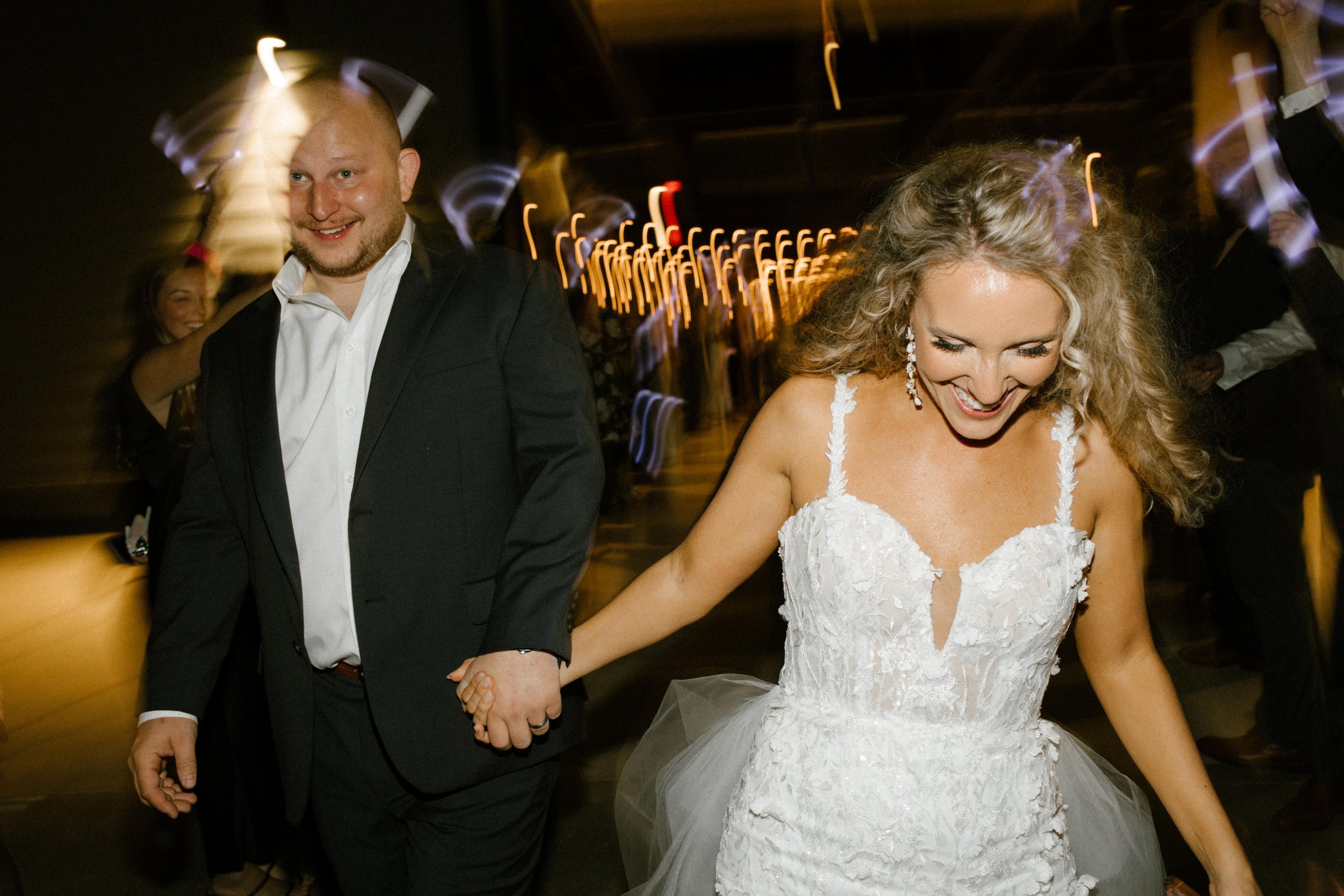 Bride and groom holding hands while running through the venue toward their wedding after party.