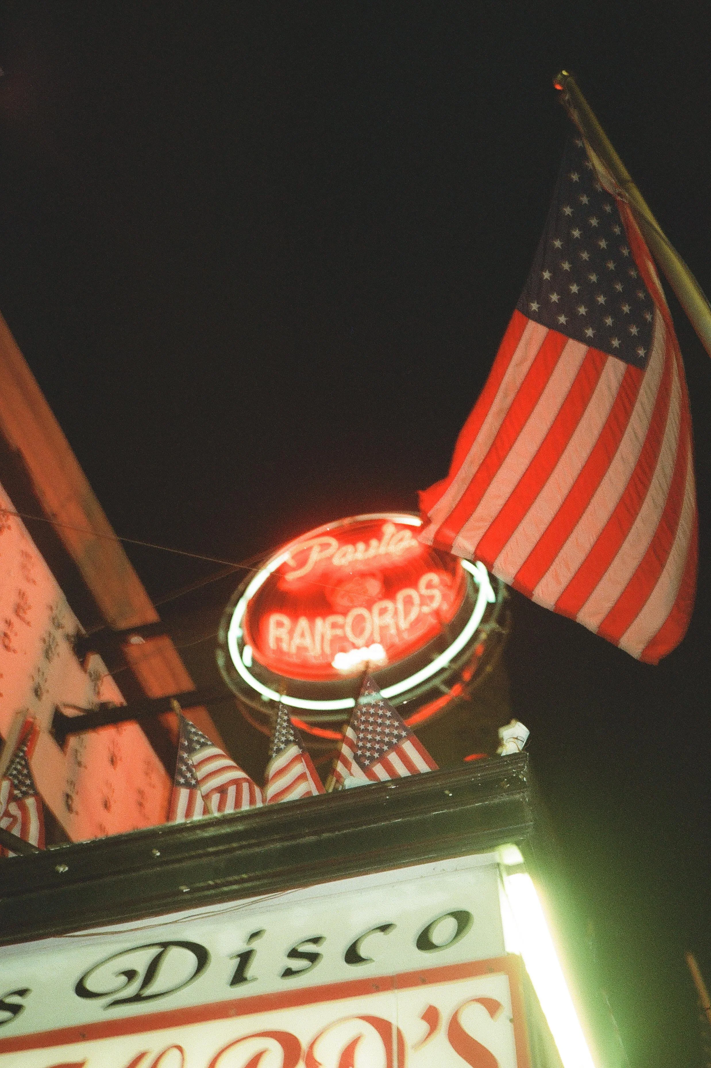 Neon sign and American flags outside a disco nightclub where guests gather for wedding after parties.