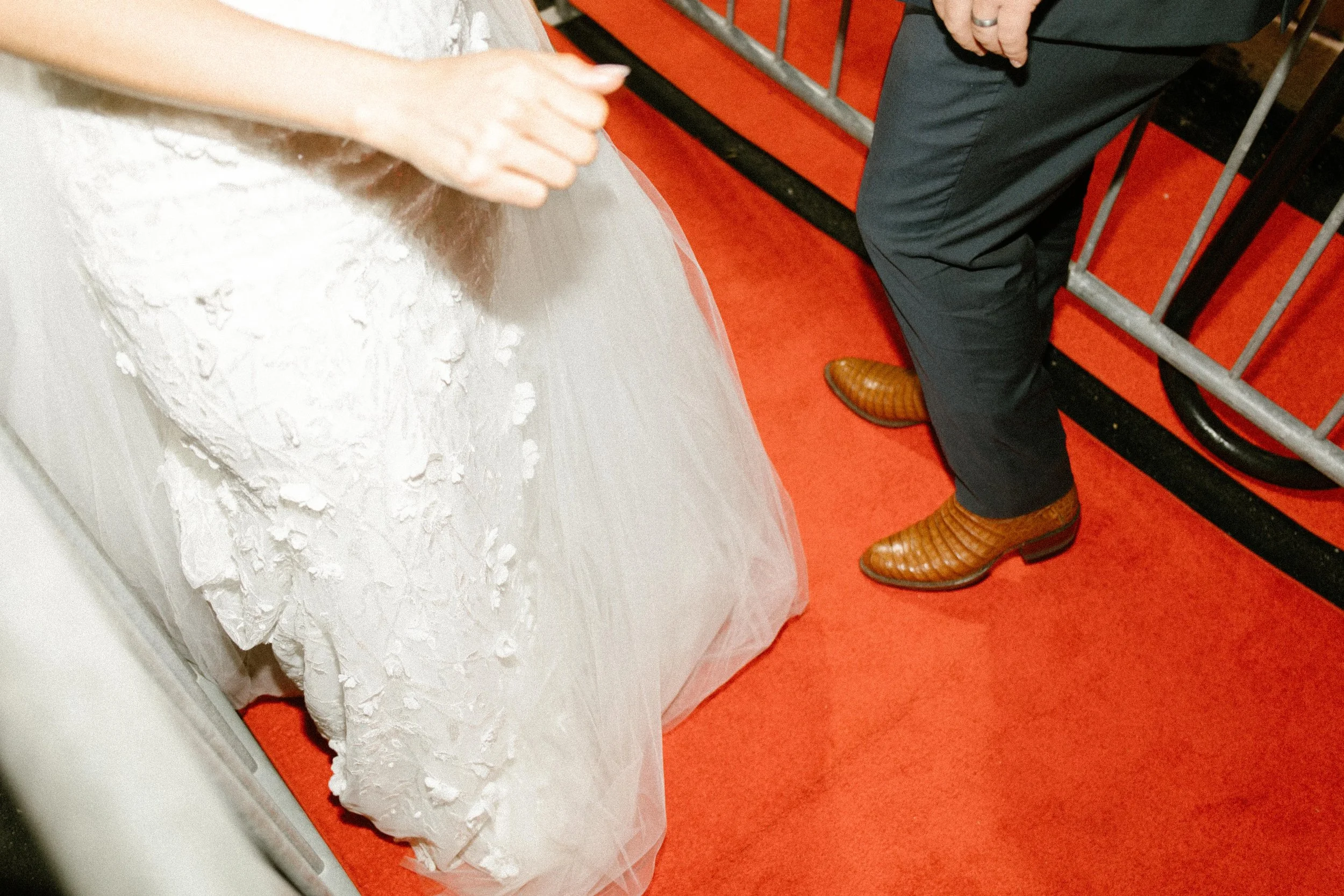 Bride and groom walking along a red carpet hallway during a late-night wedding after party.