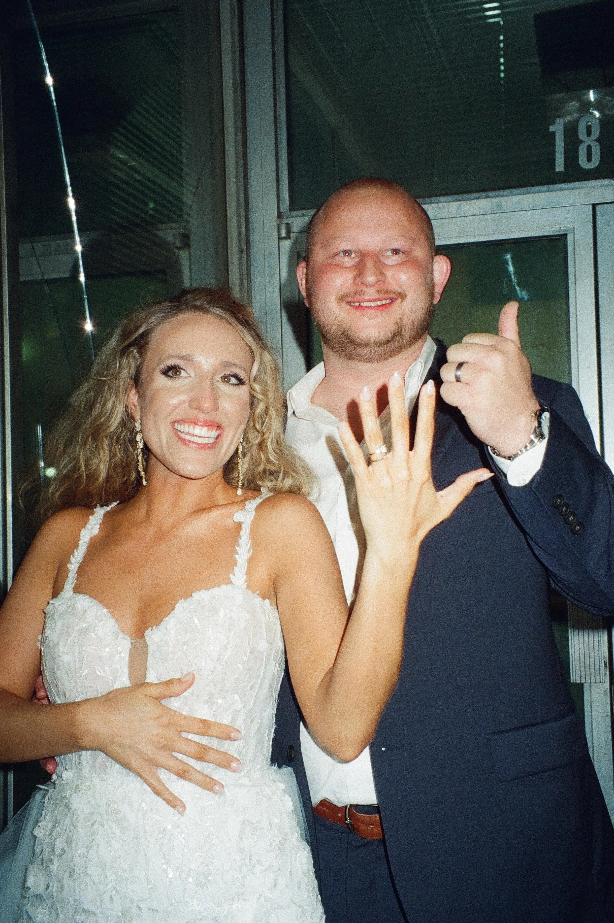 Newlyweds smiling and showing their wedding rings during their wedding after party celebration.