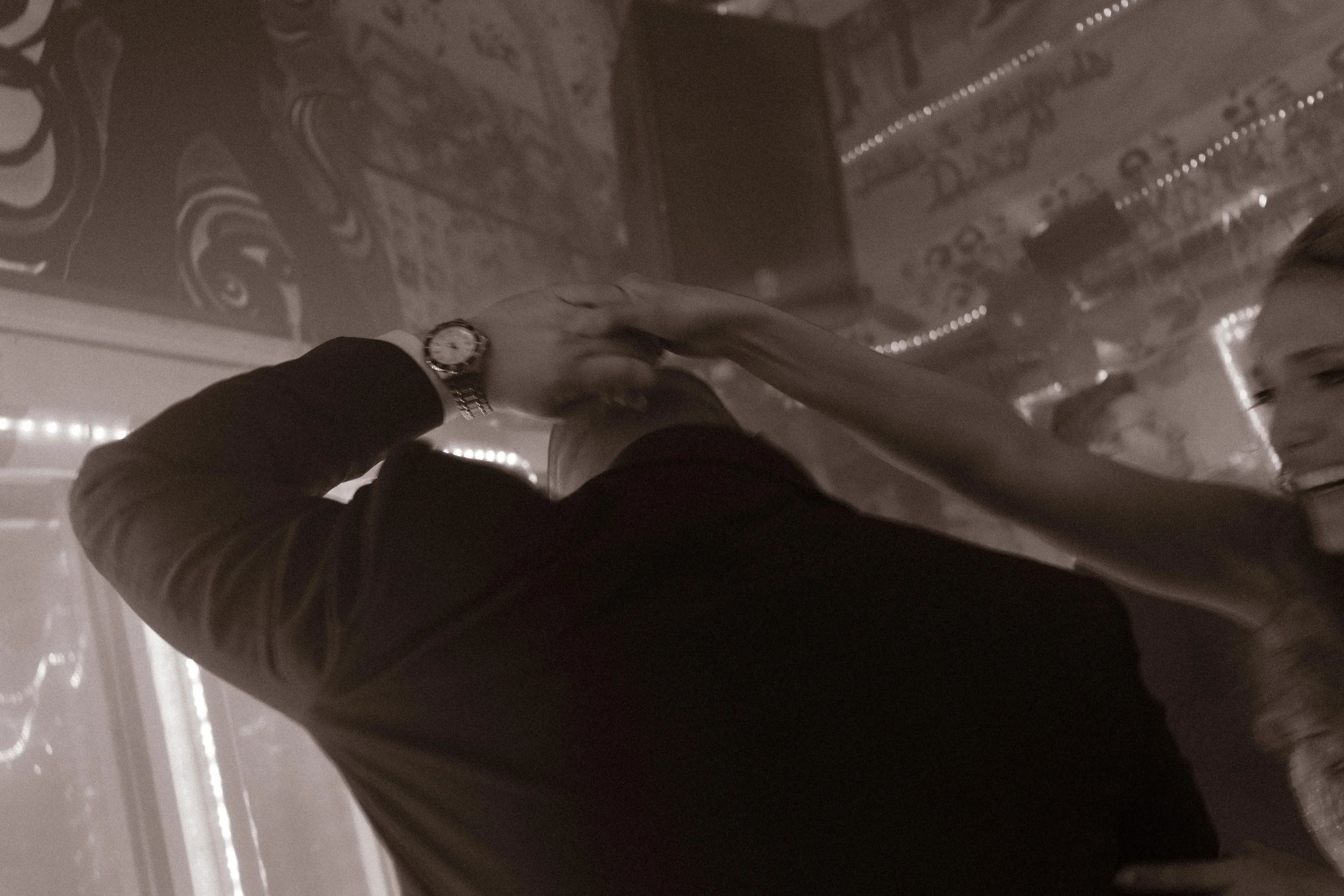 Groom dancing with raised arms on a neon-lit dance floor during wedding after parties.