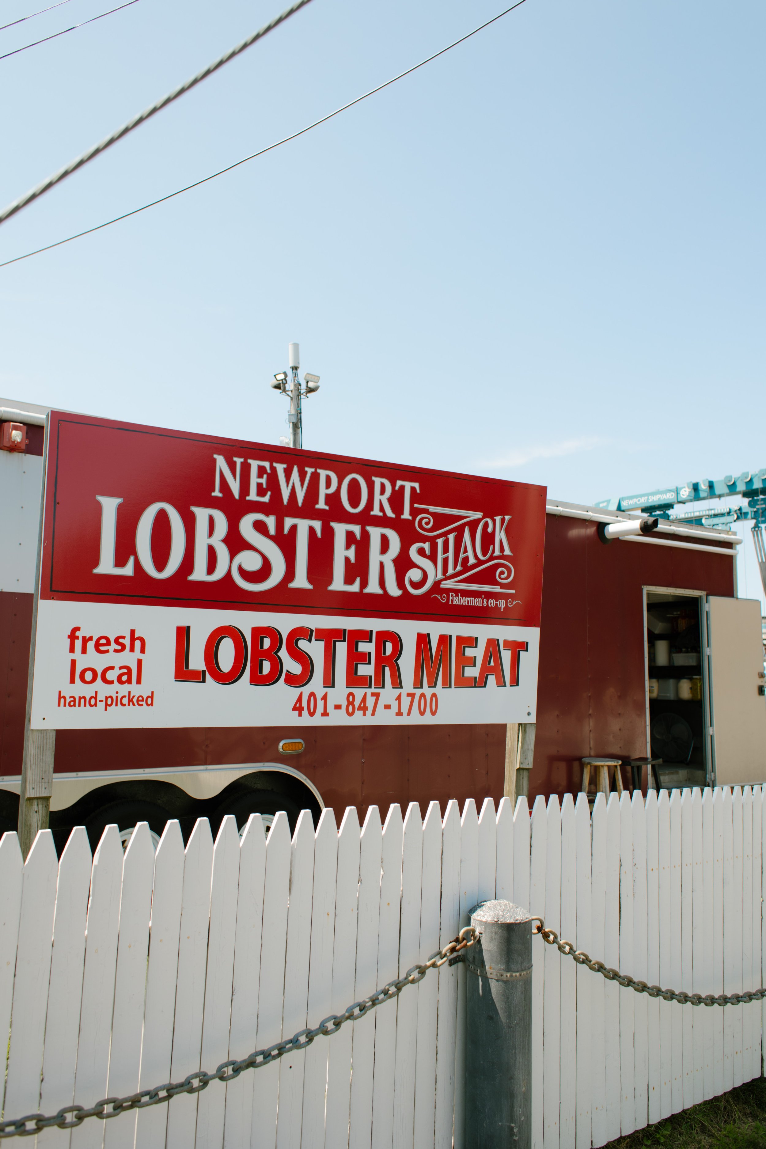 Newport Lobster Shack sign and white fence along harbor in Newport Rhode Island