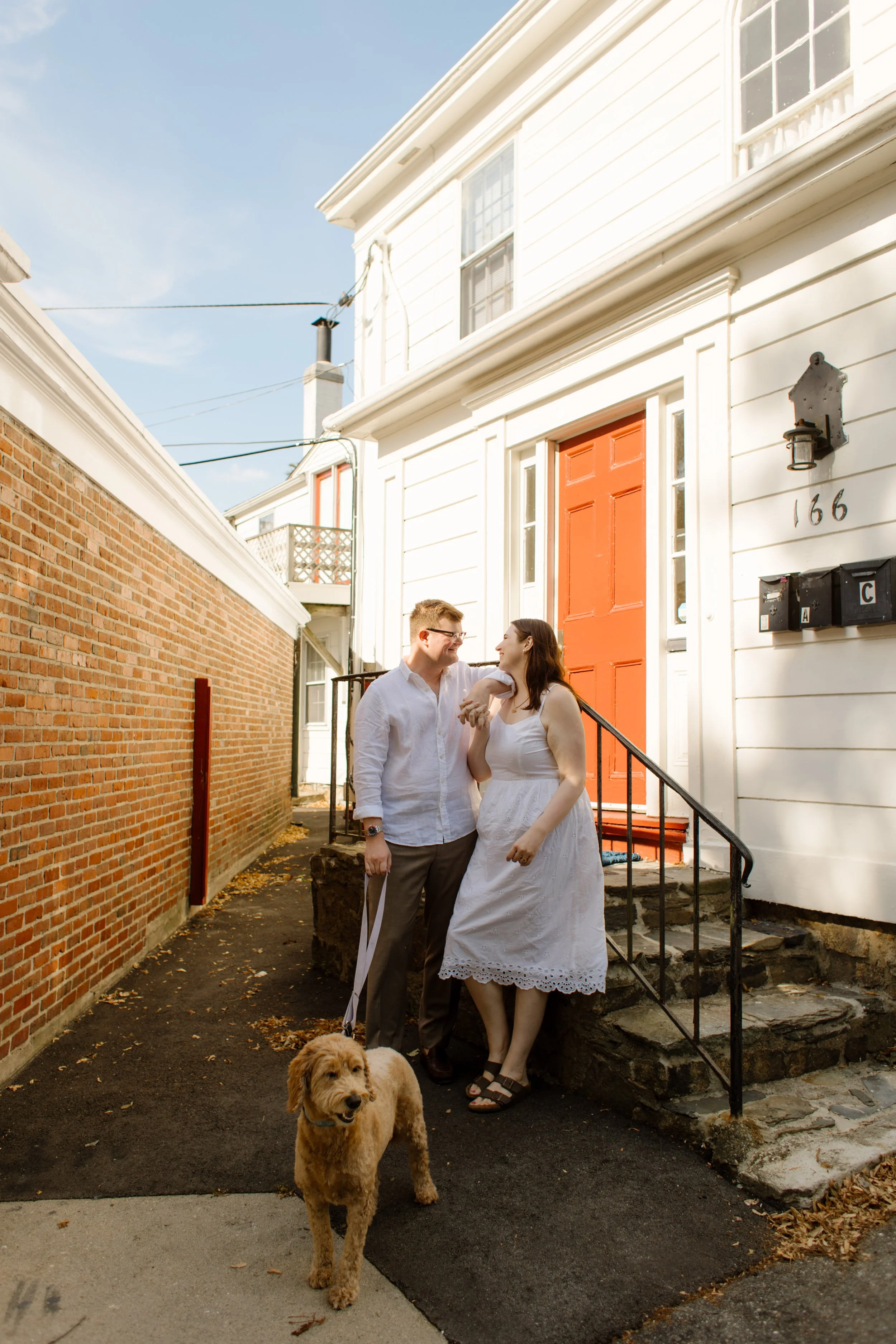 Couple with their dog outside historic Newport home with bright orange door