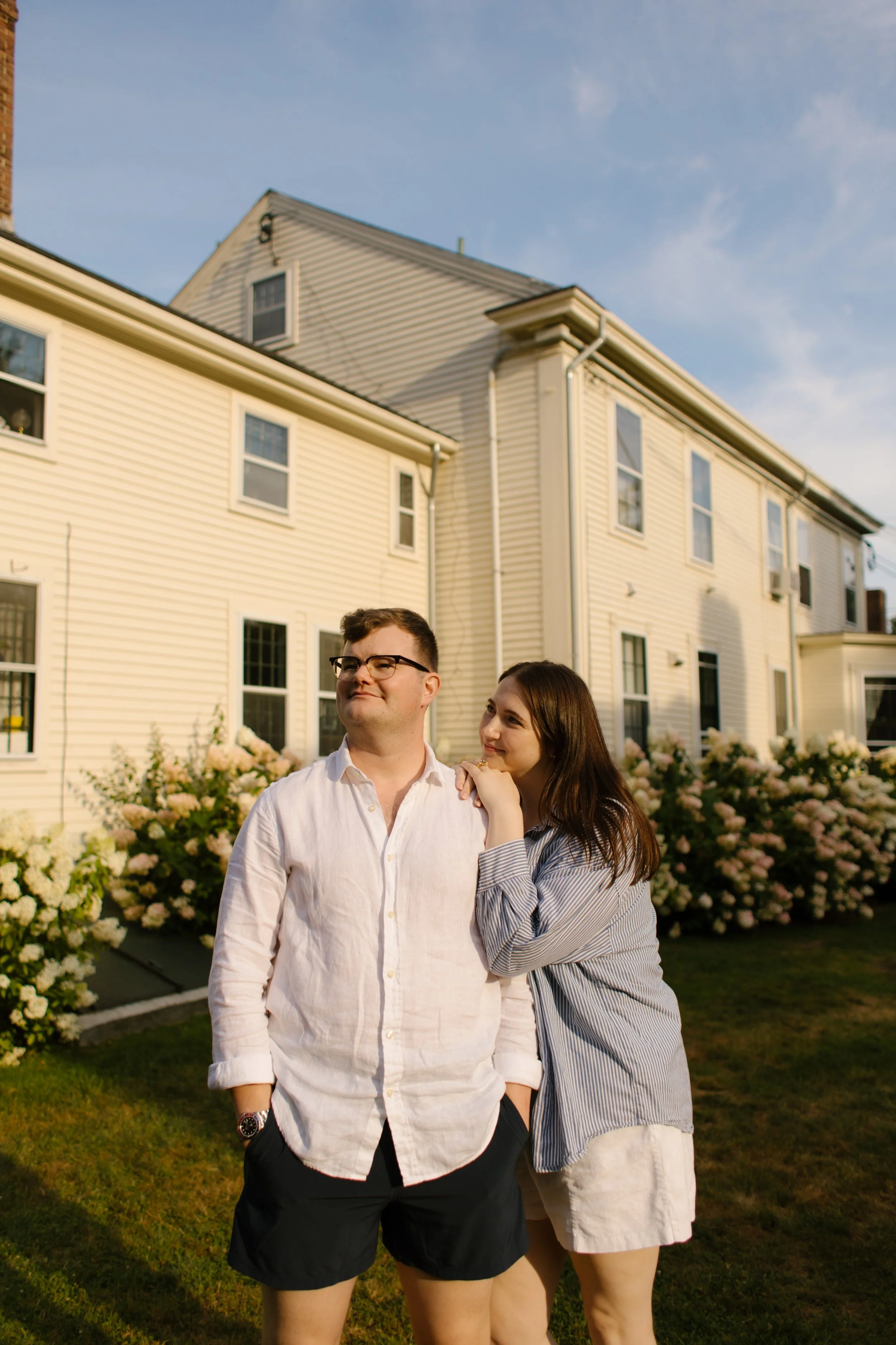 Couple standing in front of historic Newport home with blooming garden flowers
