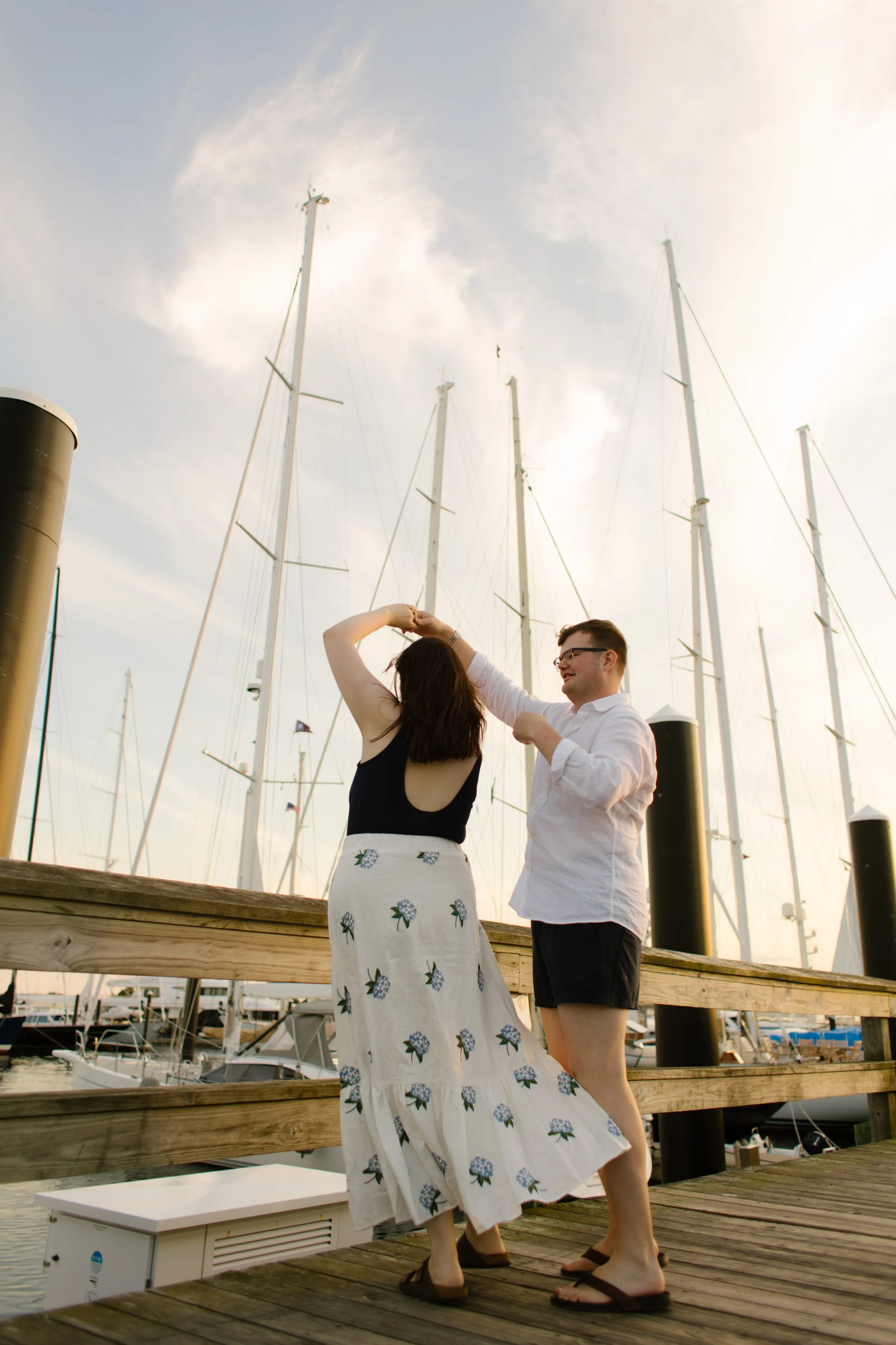 Couple dancing on harbor dock with sailboats during Newport Rhode Island engagement photos