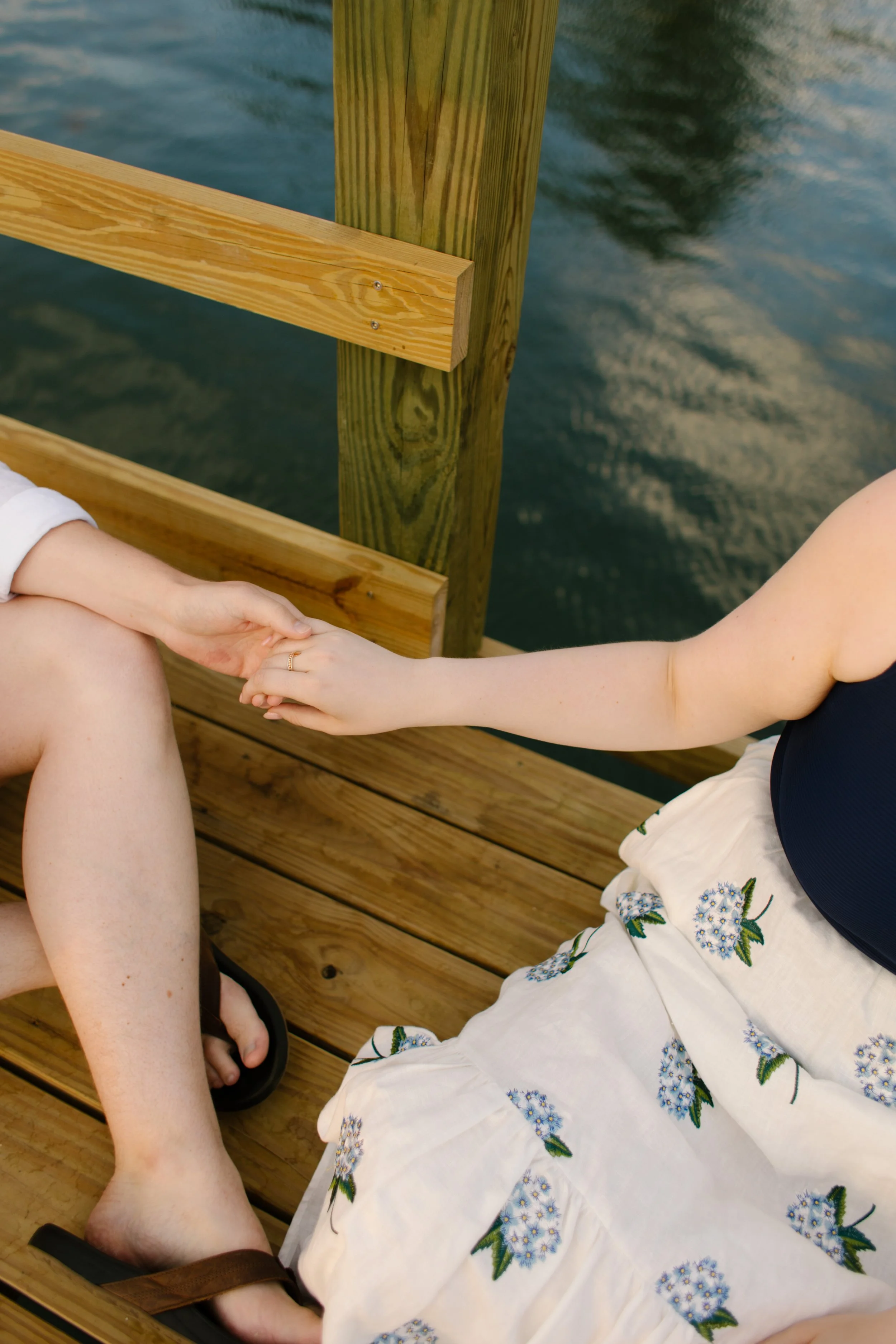 Couple holding hands on wooden harbor dock during Newport Rhode Island engagement photos