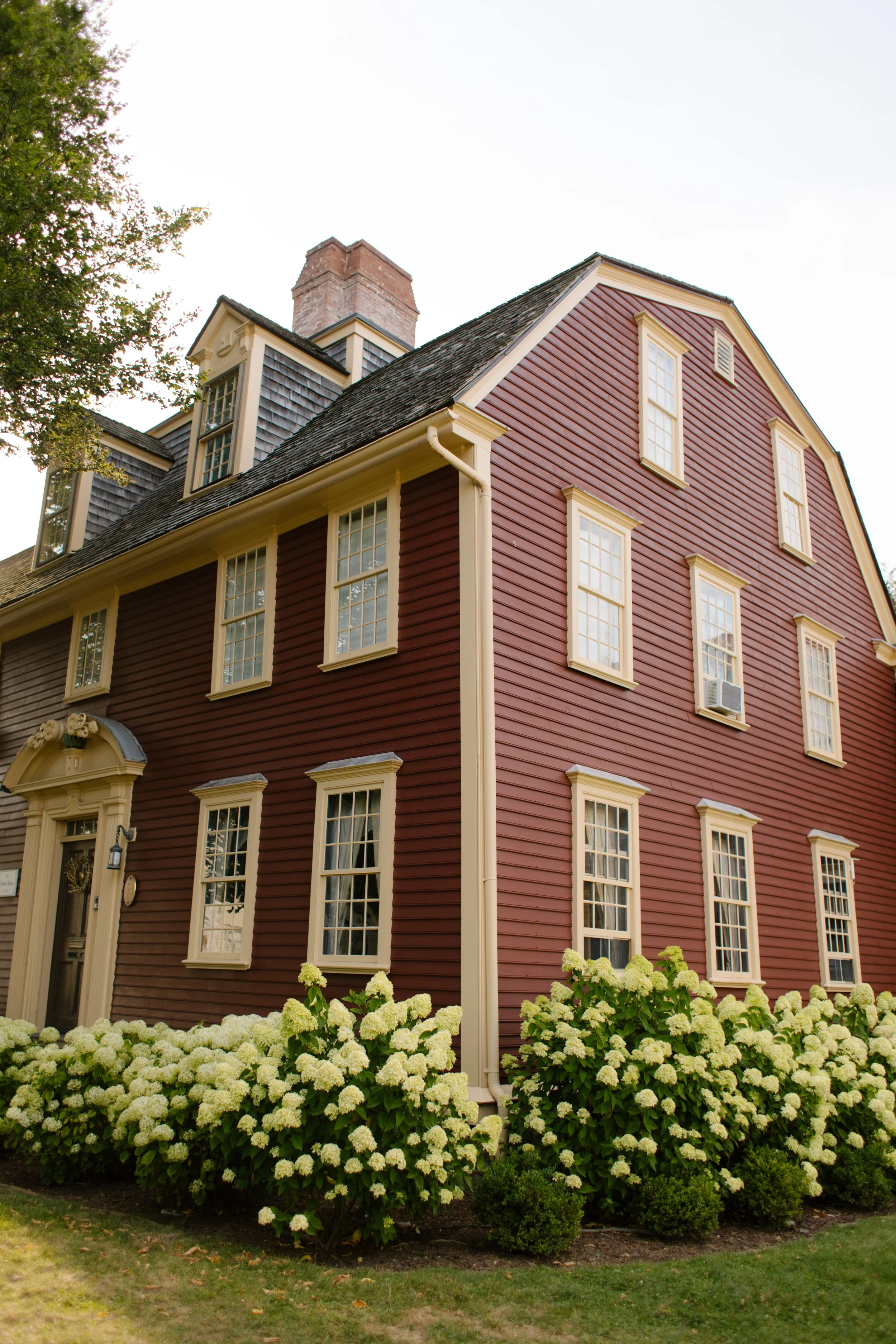 Historic red colonial home with blooming white garden flowers in Newport Rhode Island