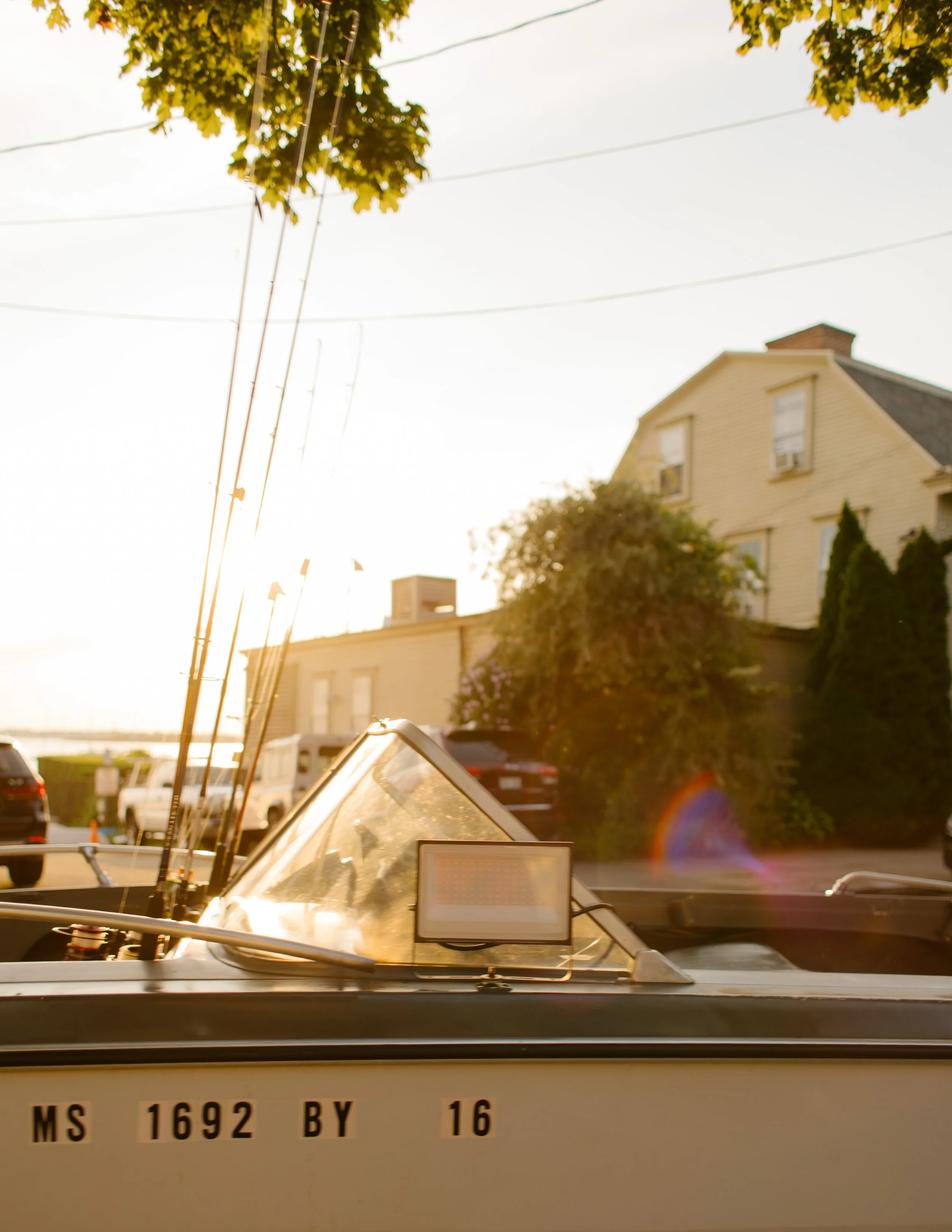 Boat parked along quiet Newport harbor street at golden hour