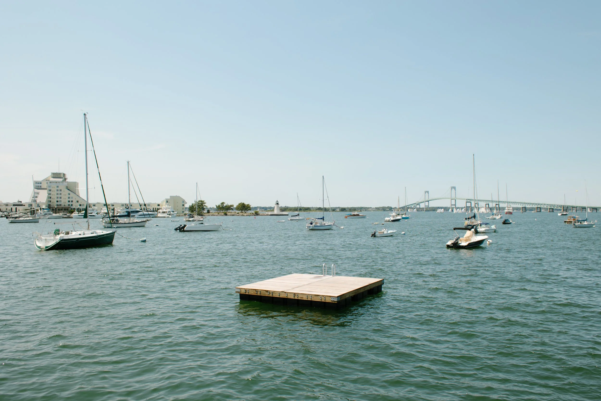 Boats floating in Newport harbor with bridge in the distance during Newport Rhode Island engagement photos