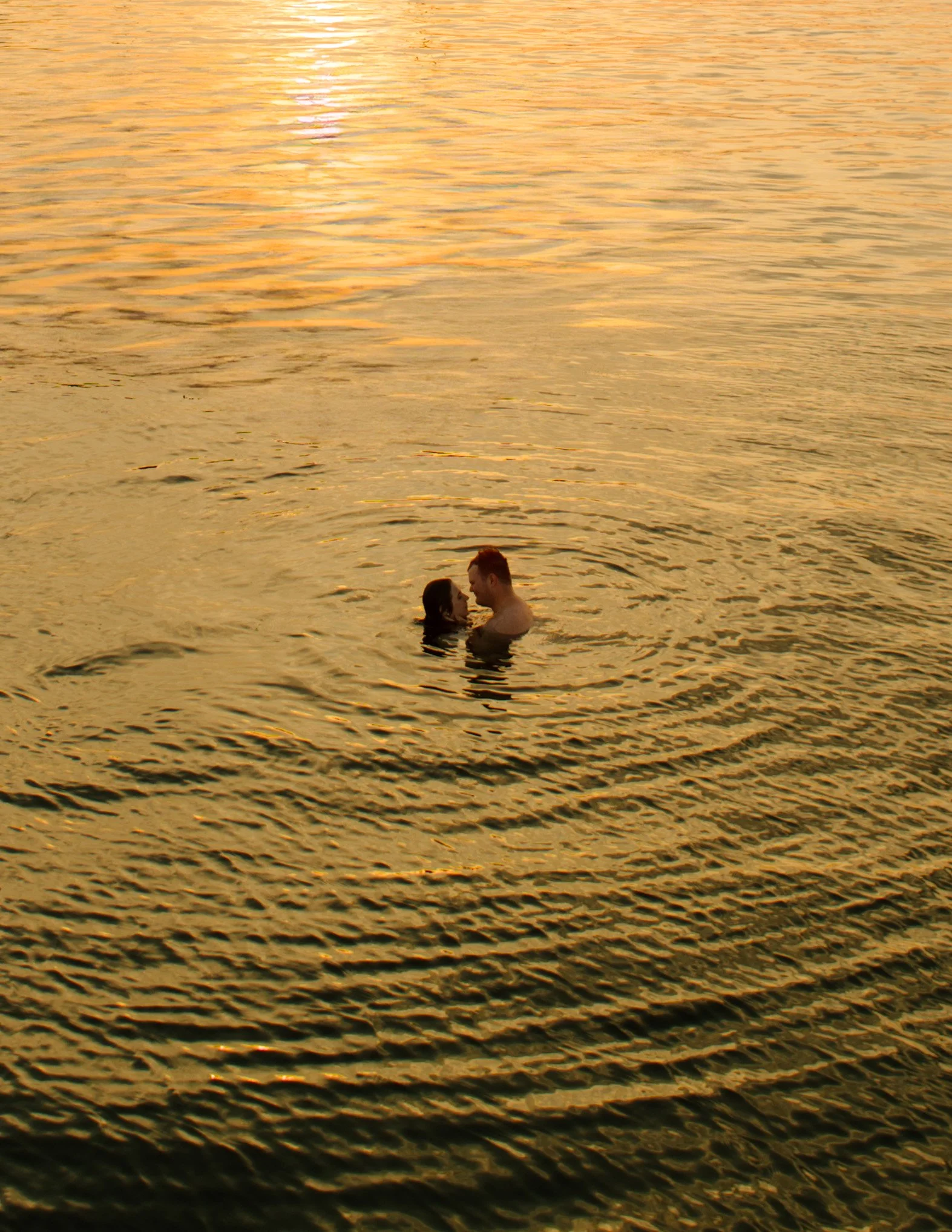 Couple embracing in the water at sunset during Newport Rhode Island engagement photos