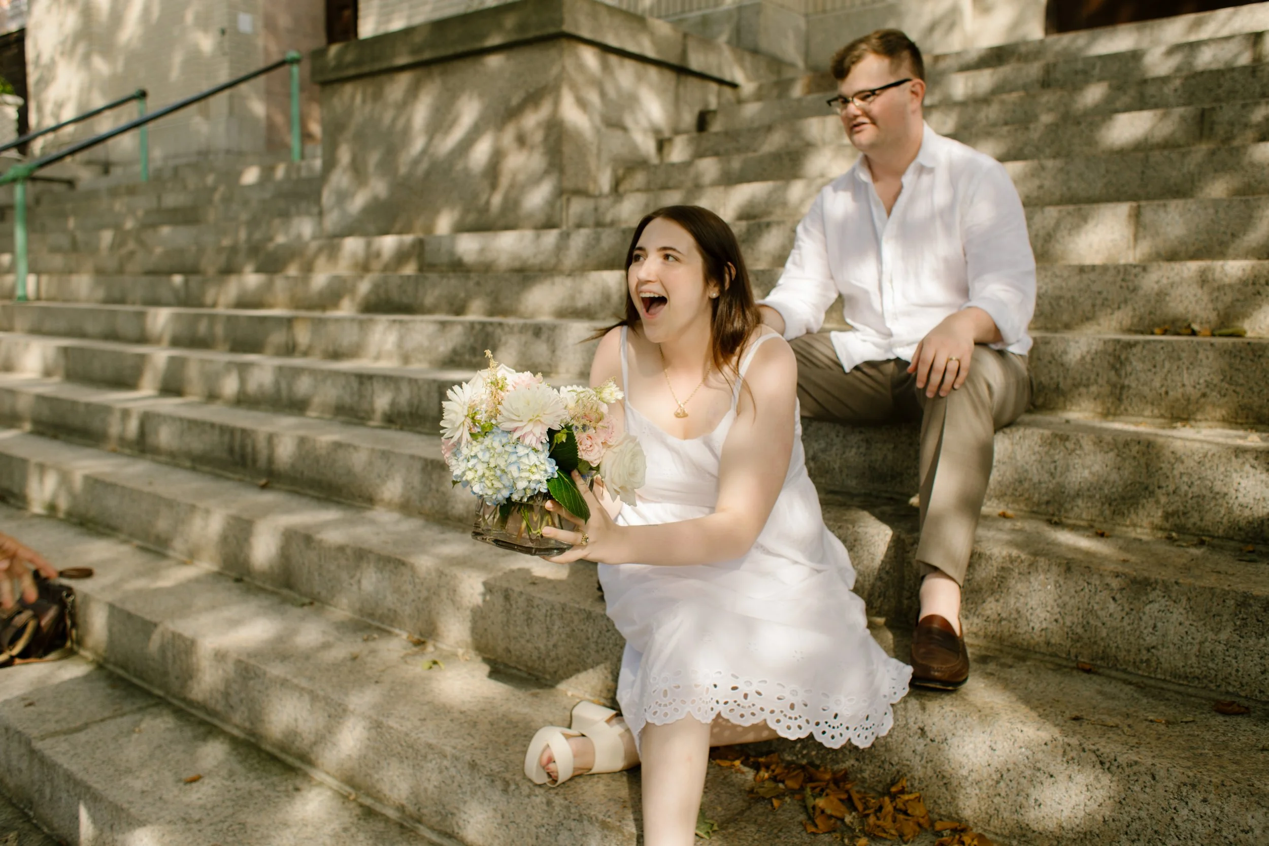 Couple sitting on historic stone steps laughing during Newport Rhode Island engagement photos