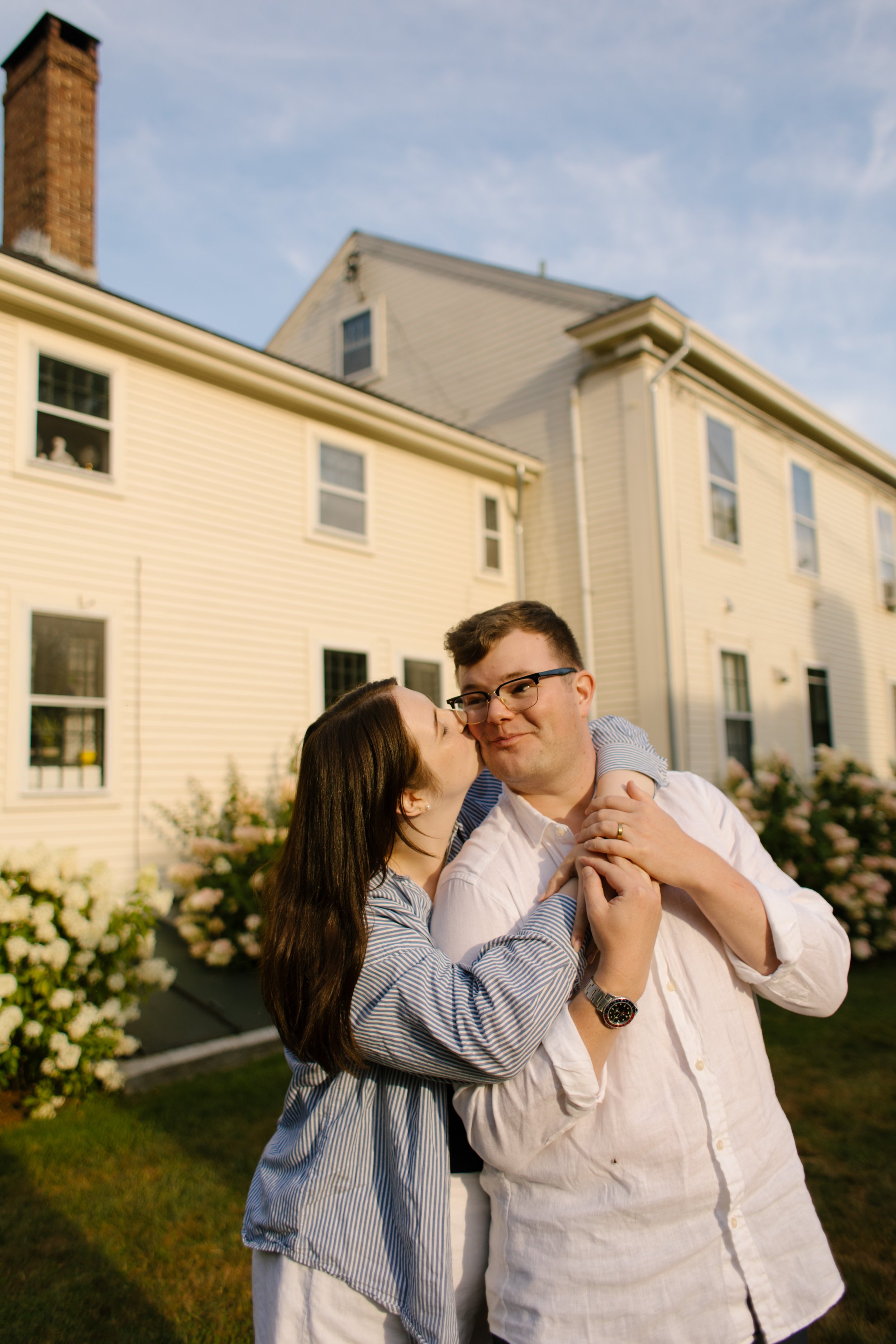 Couple embracing in garden outside historic Newport home during Newport Rhode Island engagement photos