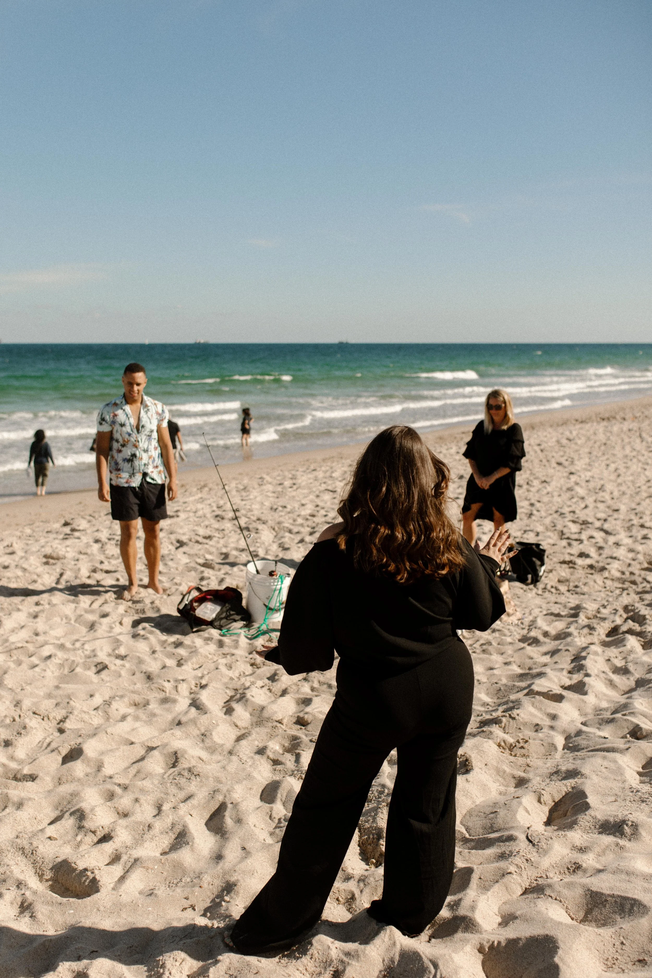 Woman on the beach turning with her hand raised in surprise, body language capturing the exact second everything starts to shift