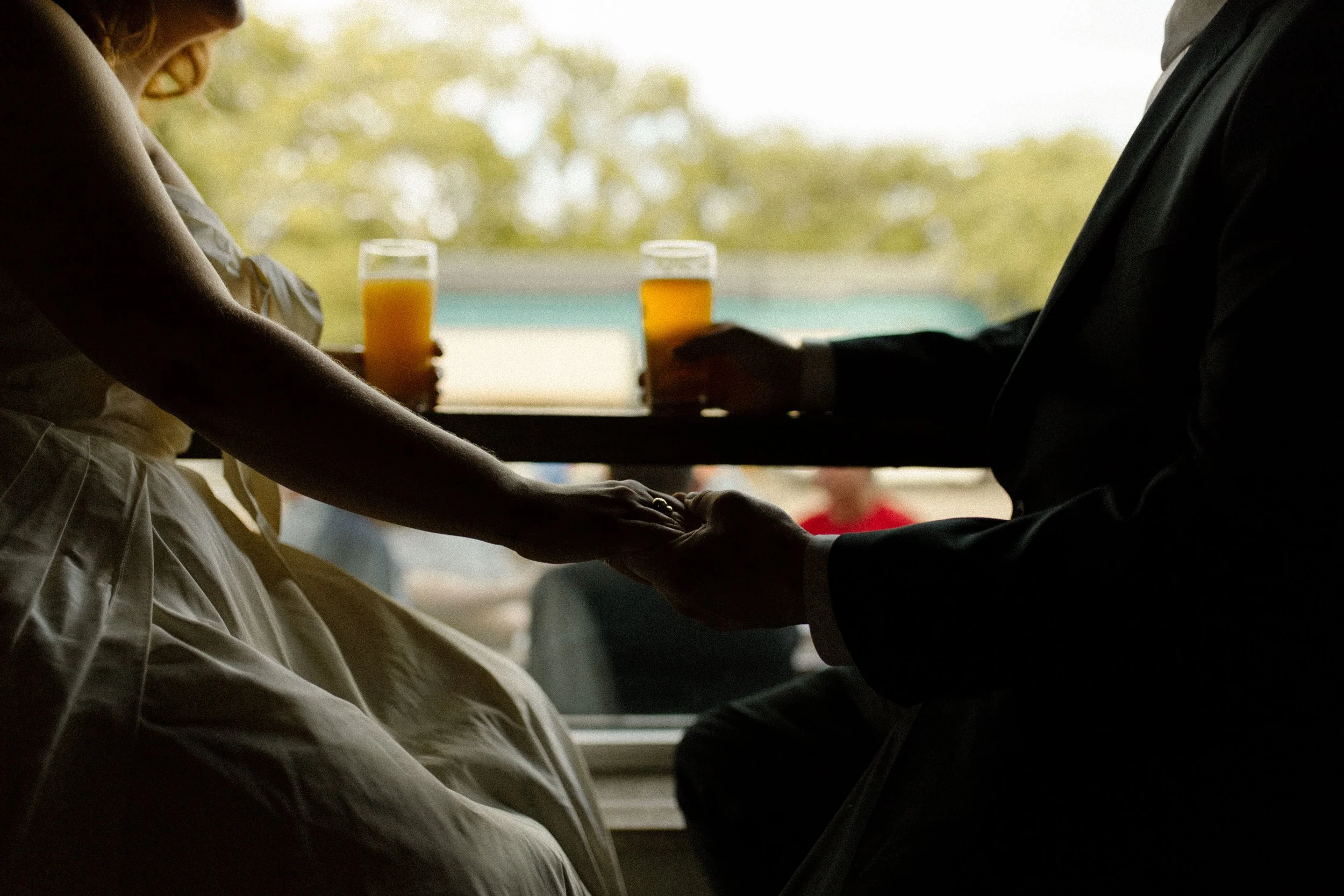 Silhouetted couple clinks drinks while holding hands by a window, captured in a warm and intimate pre wedding photos moment.