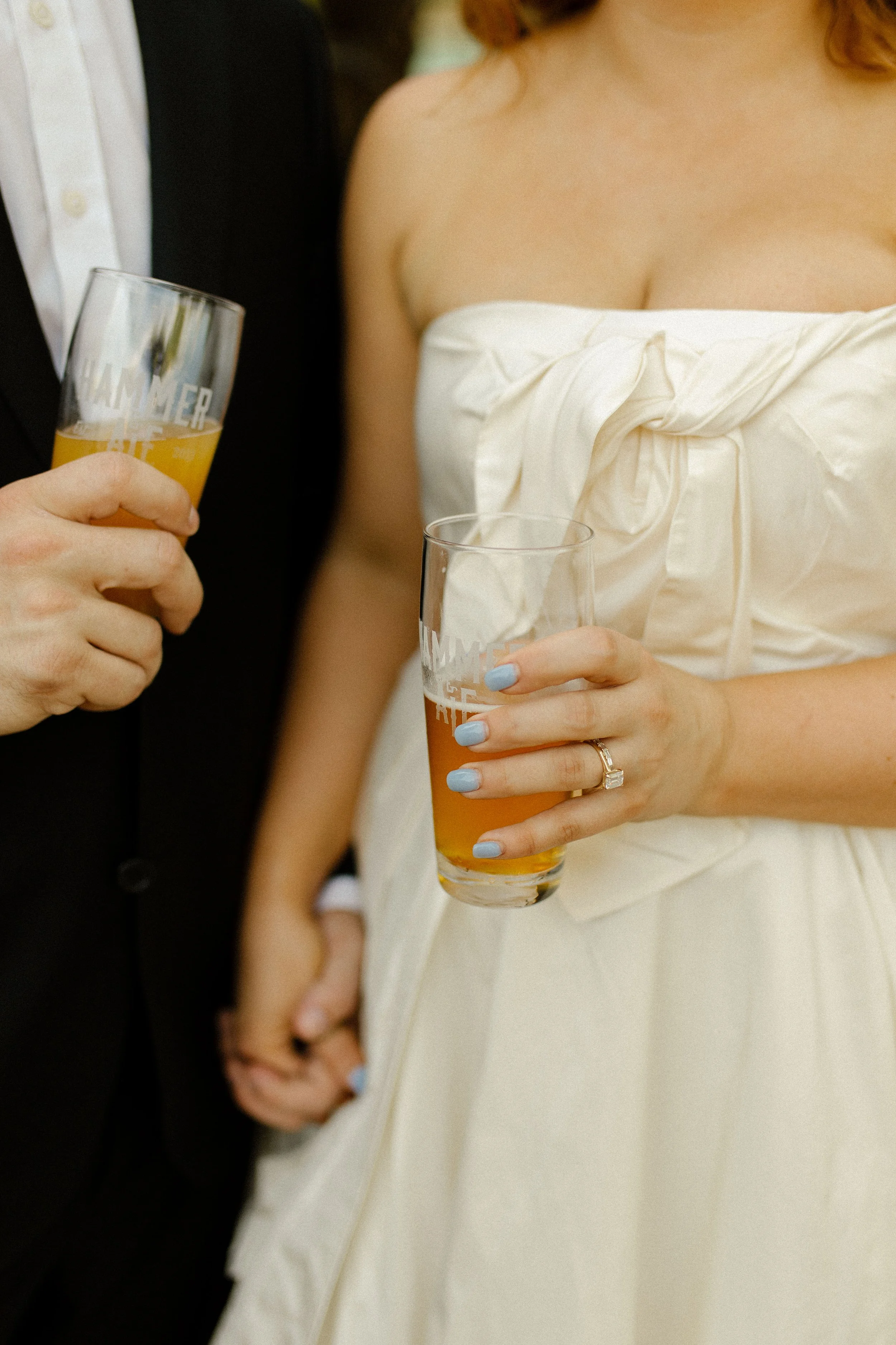 Couple sits together outside a brewery window, drinks in hand, leaning into each other in a relaxed and candid moment.