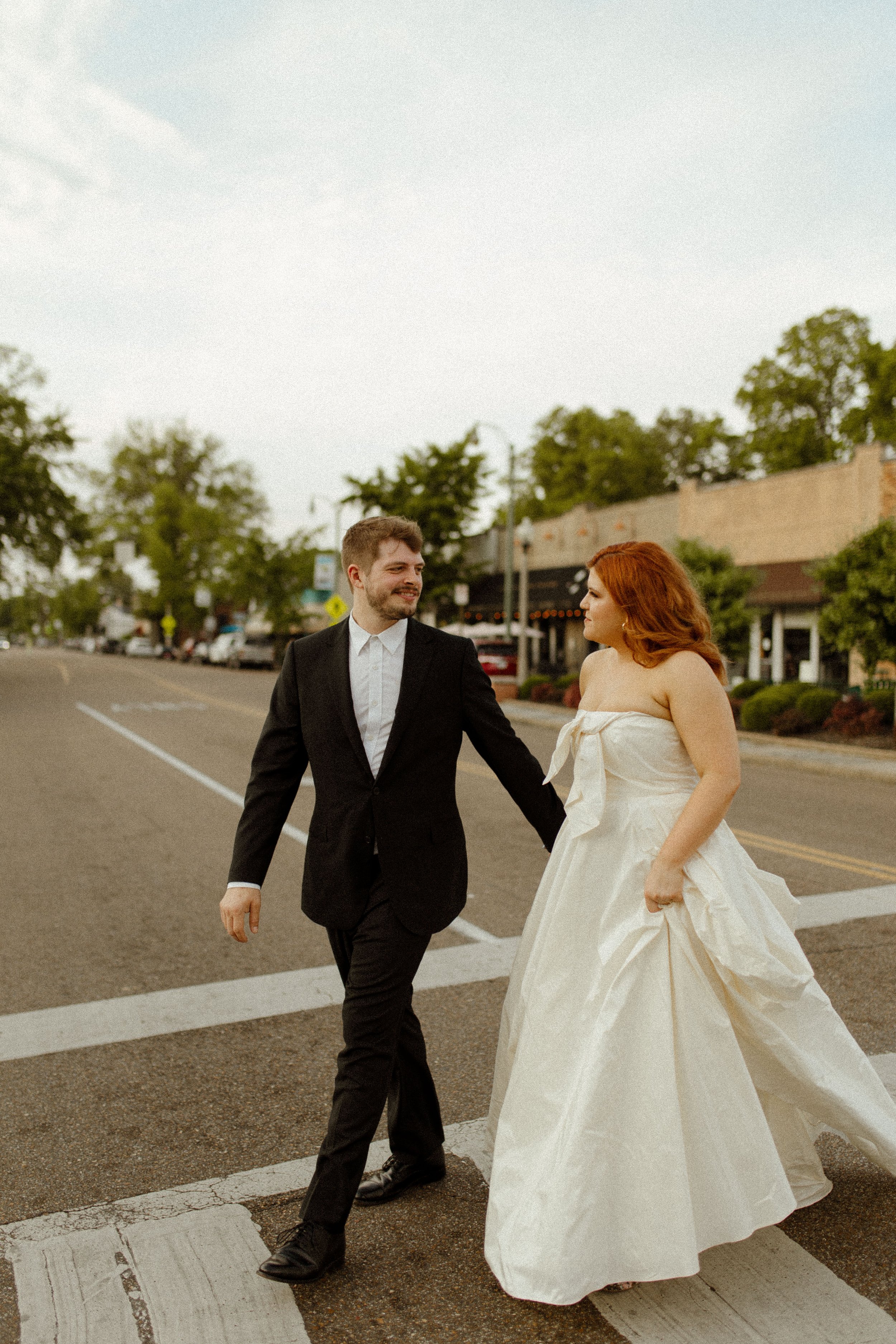 Couple stands close together under a large leafy tree on a quiet street, creating a calm and cinematic pre wedding photos moment.