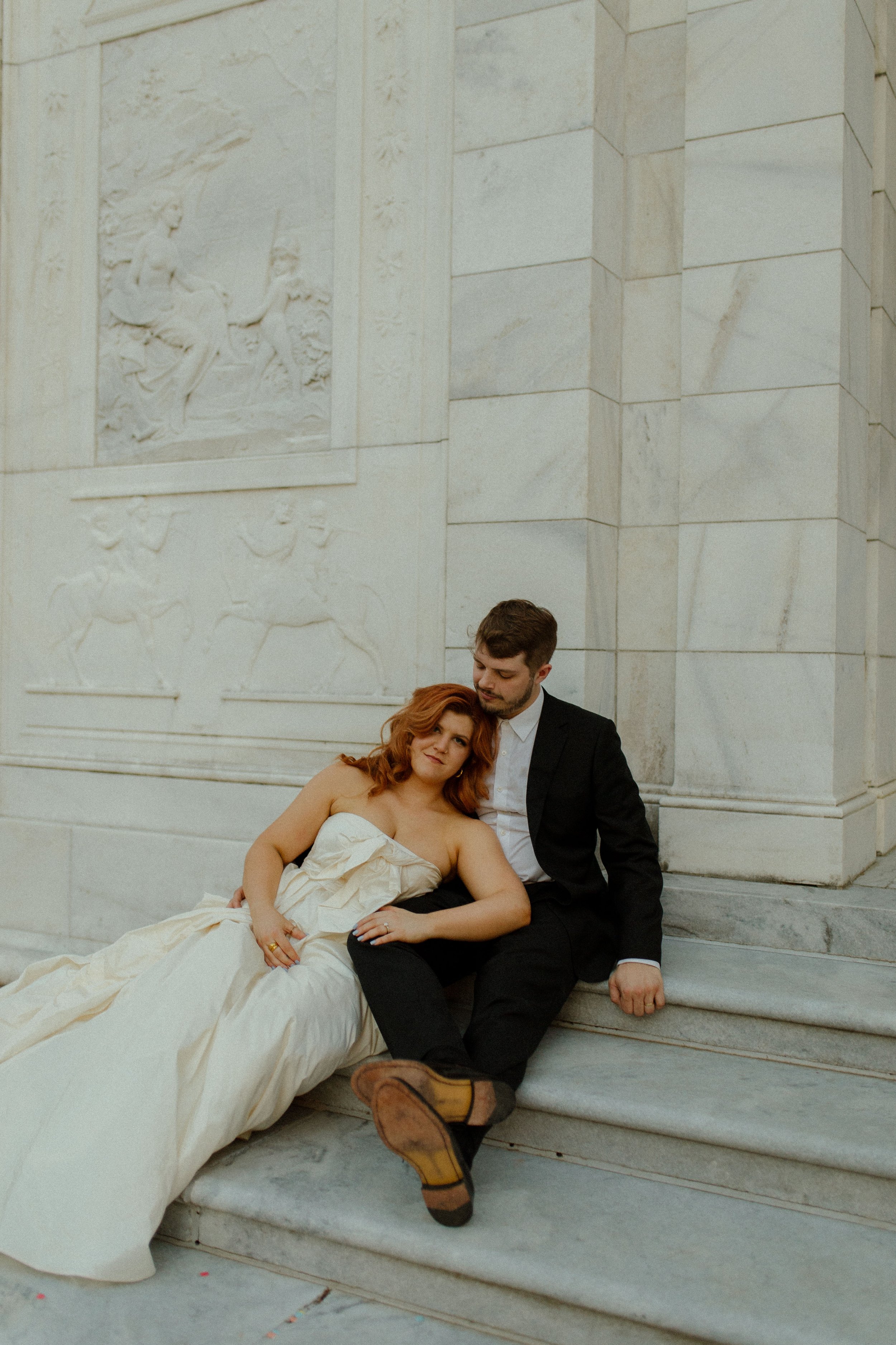 Bride leans into groom as they sit on stone steps, both relaxed and connected in a soft and intimate pre wedding photos scene.