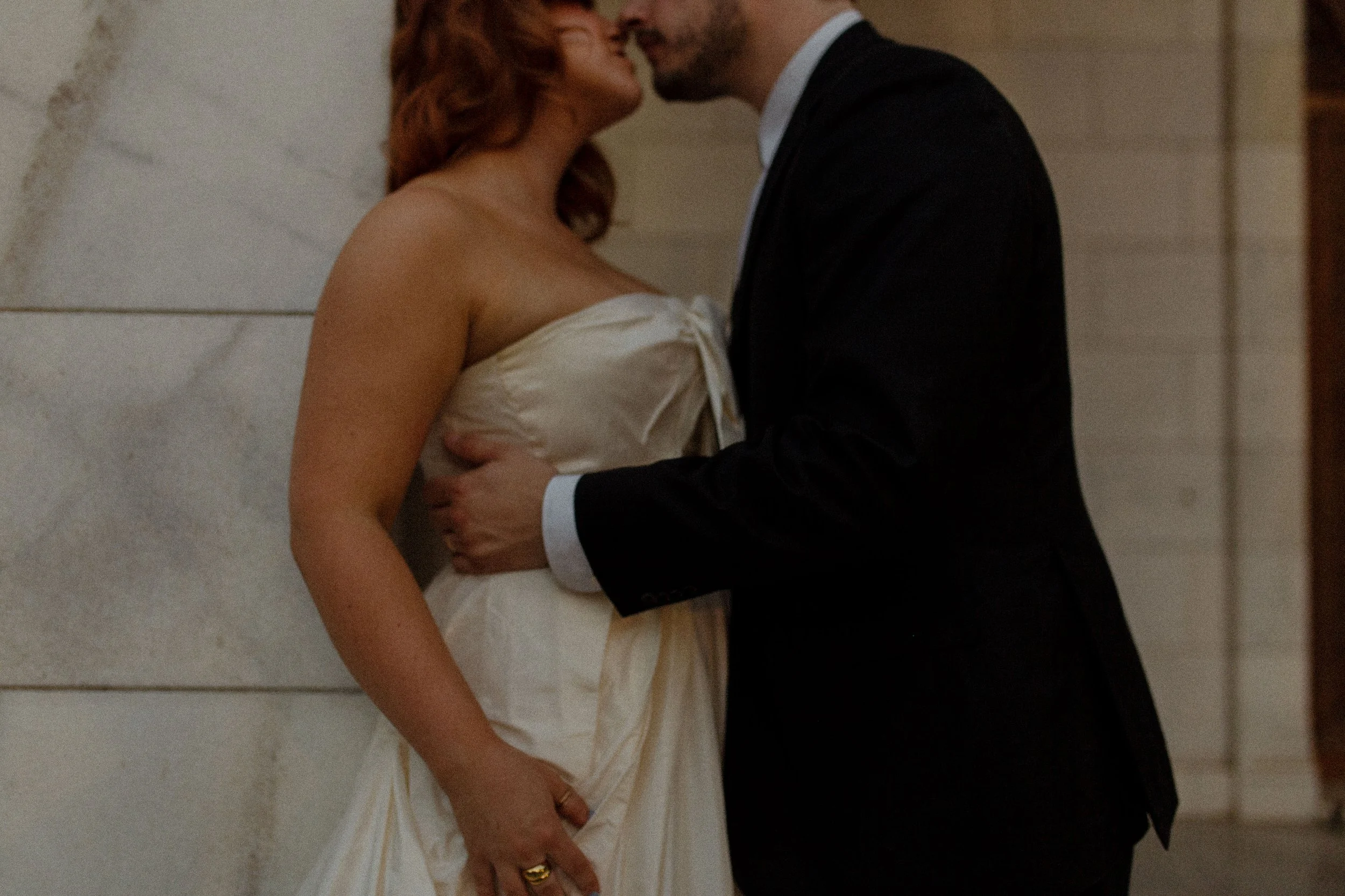 Couple leans in for a kiss against a stone wall, creating a moody and intimate pre wedding photos scene.